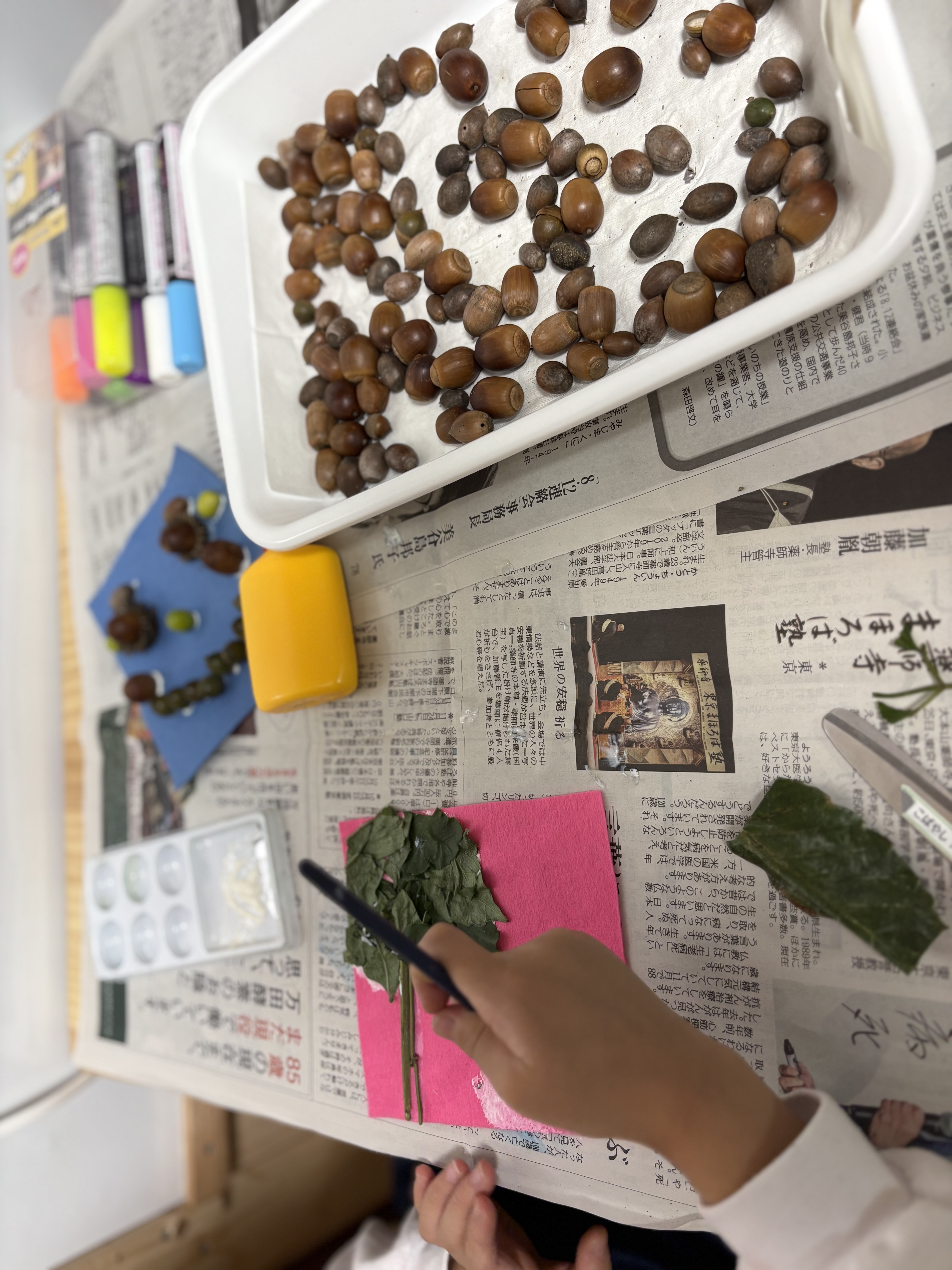 小さなどんぐりやパーツをボンドで丁寧に貼り付け、指先の巧緻性を高めるどんぐりアート制作中の手元
