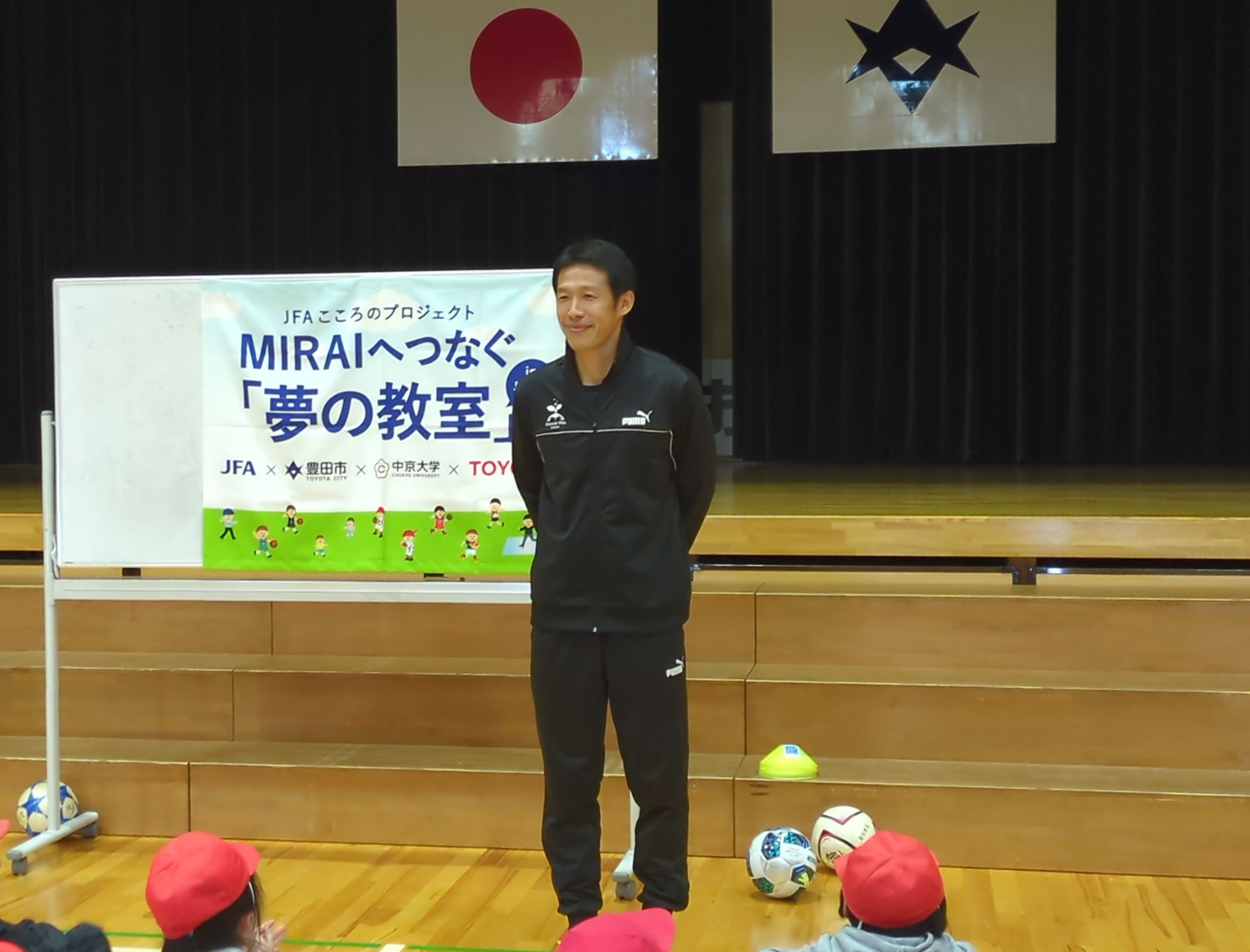 体育館で子どもたちと協力ゲームを行い、笑顔でハイタッチをする様子