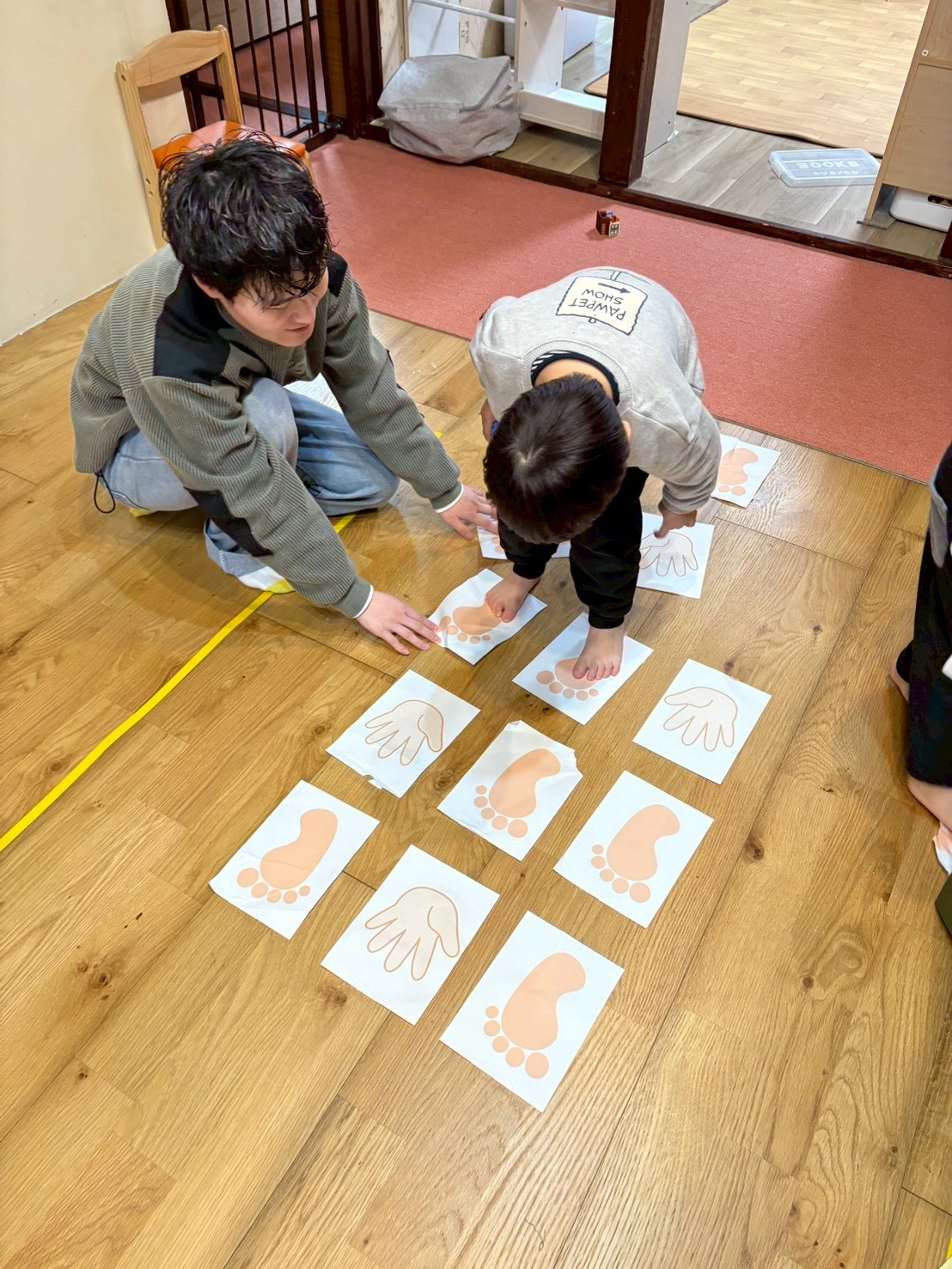 ボール遊びや手足のマークを使った運動遊びのシーン。「先生ヘタクソ！」と笑いながら、自己肯定感を育む子どもたち
