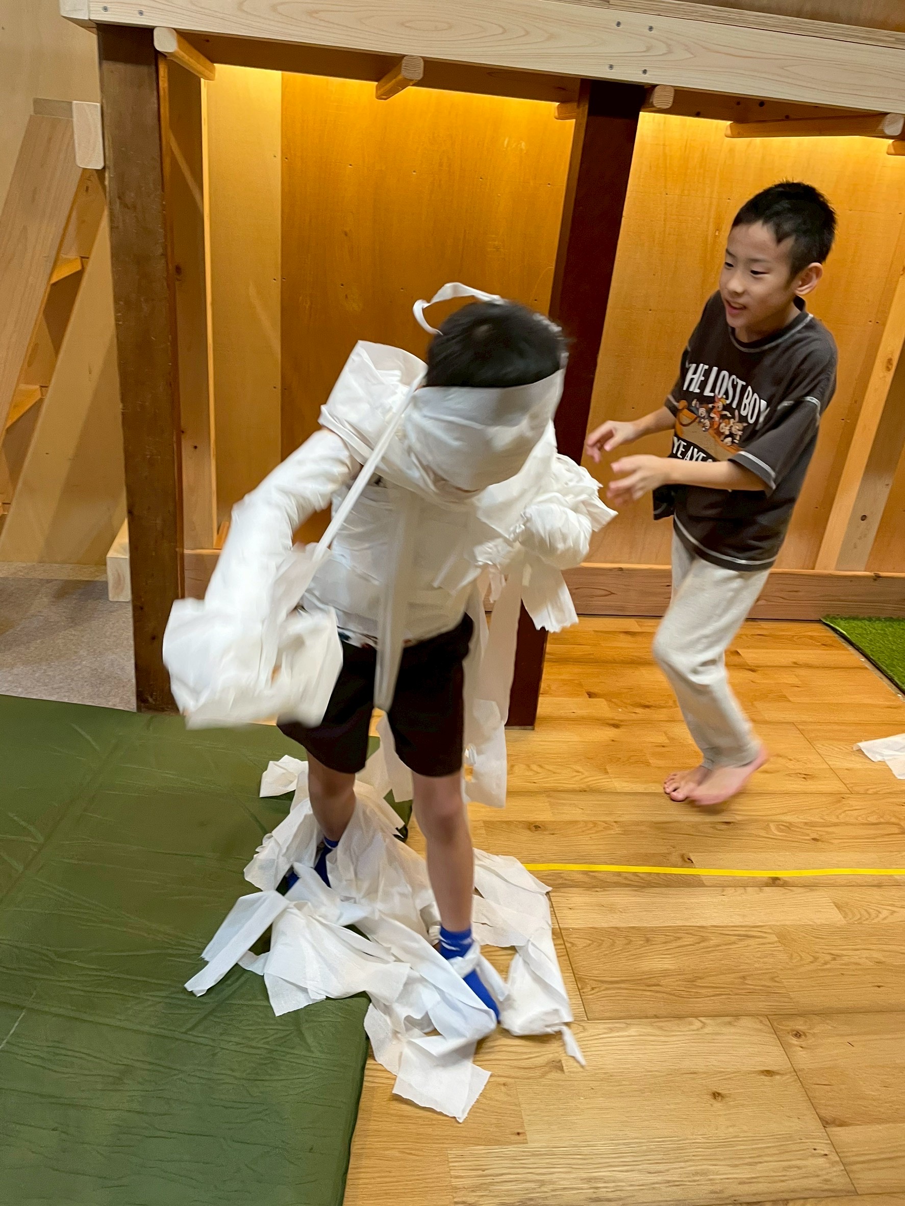 完成したミイラを囲み、達成感と喜びで最高の笑顔を見せる子どもたち
