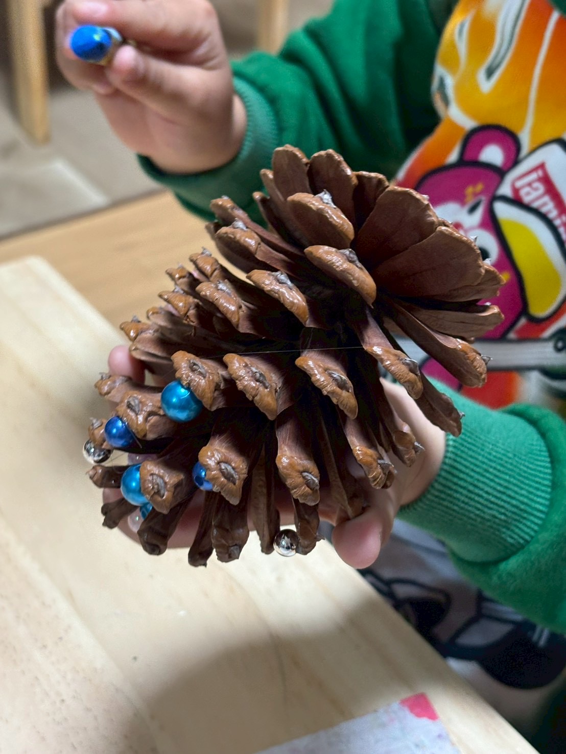 松ぼっくりにカラフルな絵の具を塗り、それが乾く「待つ時間」を「次の喜びを想像する期待の時間」に変えている活動の様子