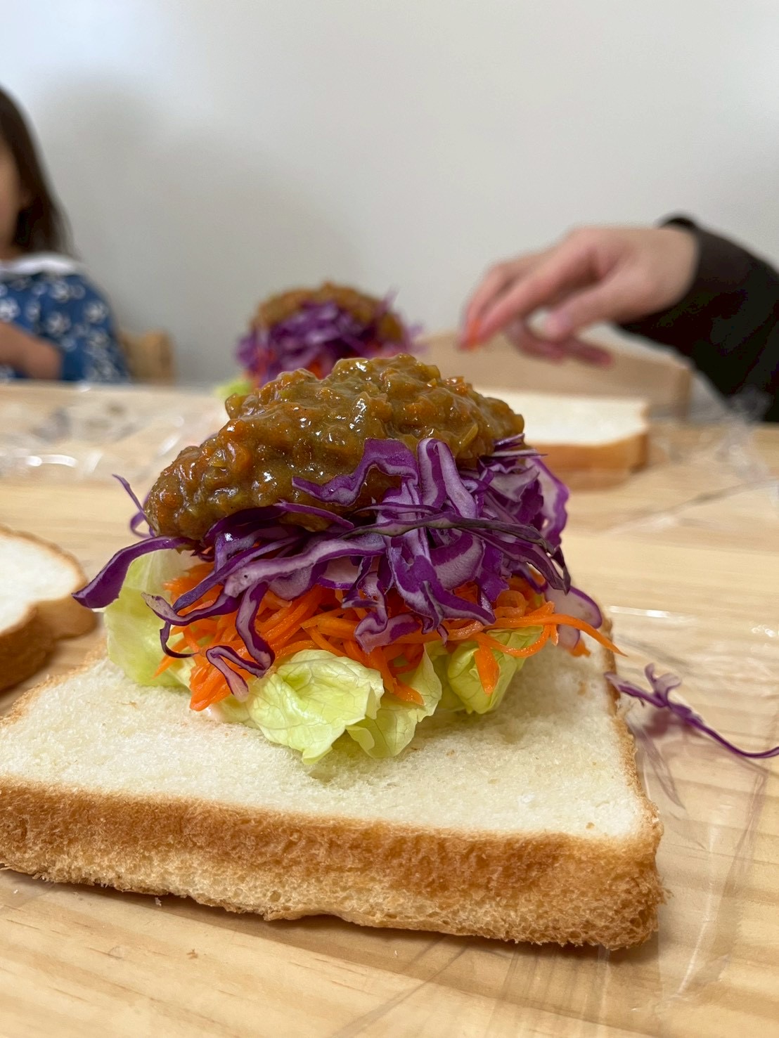 地元・北加賀屋の人気店『natural sand』のプロのスタッフから、具材の選び方やパンへの塗り方を教わりながら、真剣な表情で調理に挑戦する子どもたち