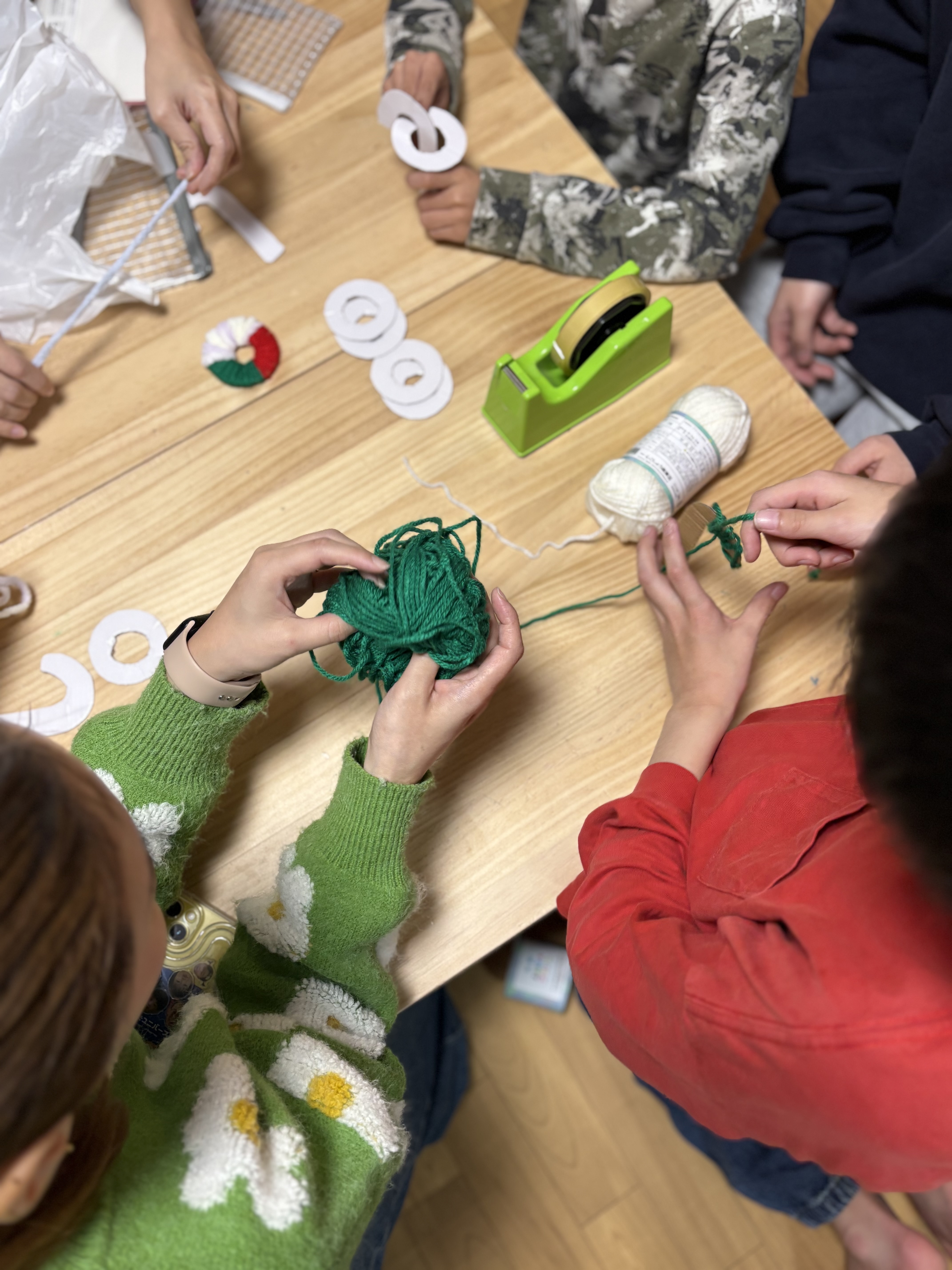 自分なりの完成図をイメージしながら、カラフルな毛糸を段ボールの型に全集中で巻き付けていく小学生のクリスマスクラフト体験