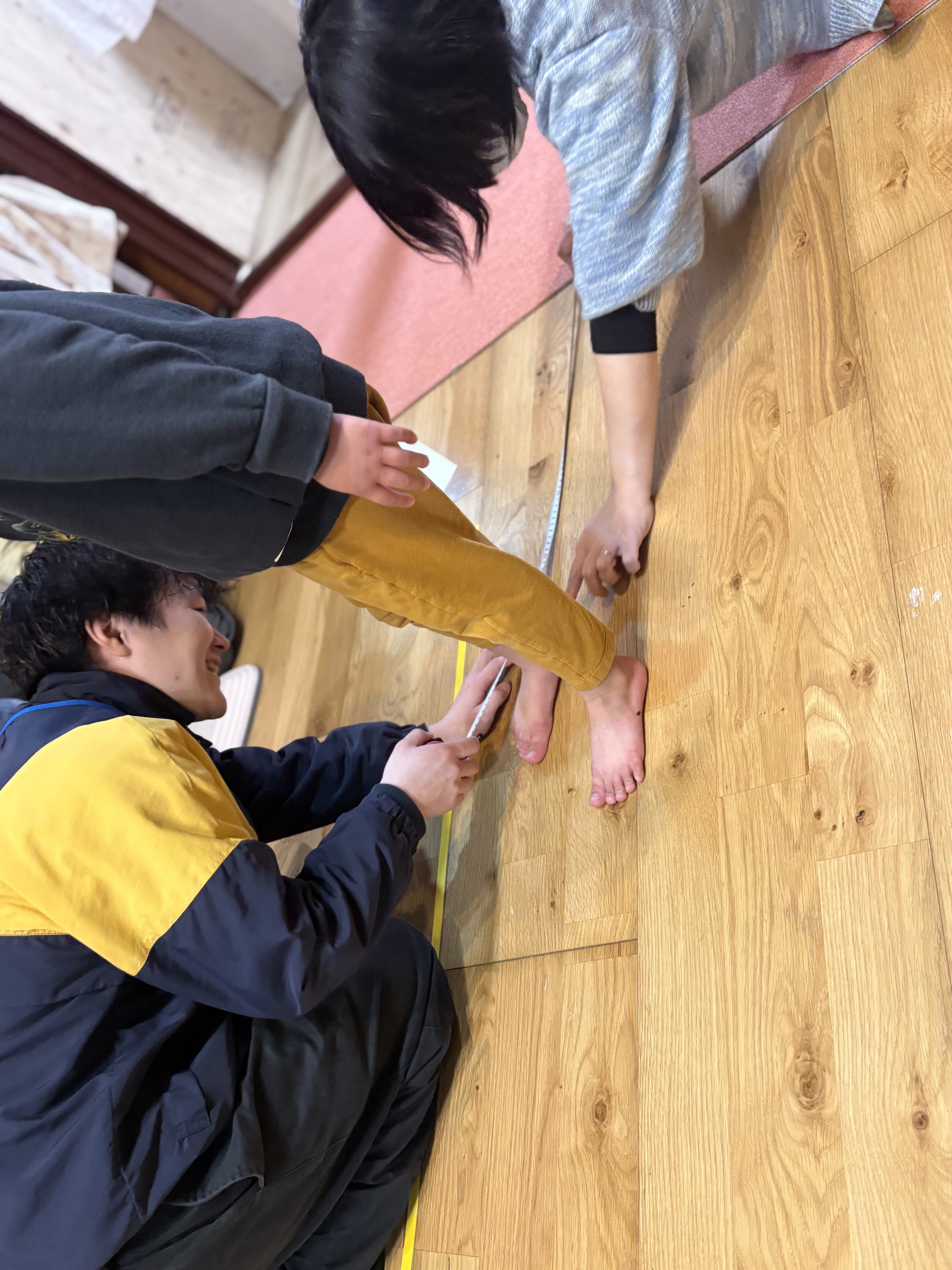 立ち幅跳びの記録をメジャーで確認し、「前より伸びた！」と小さな成功を客観的な数字で確認し、自己肯定感を育んでいる子どもの真剣な瞳