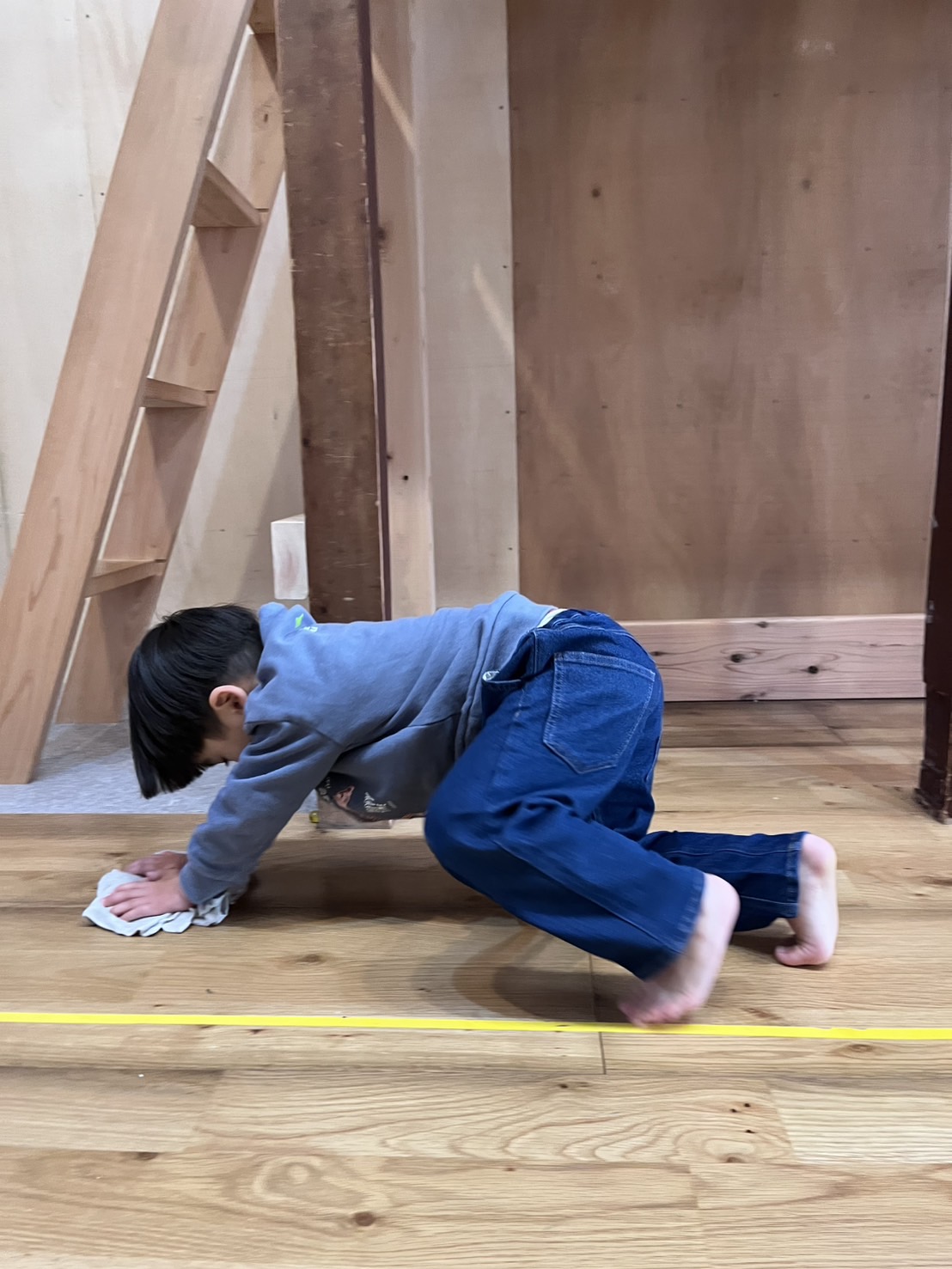 体幹を強力に鍛える雑巾がけトレーニング。四つん這いになり、重力に逆らって雑巾を押し進めることで、手足の協調運動と姿勢の安定を養う子どもの姿