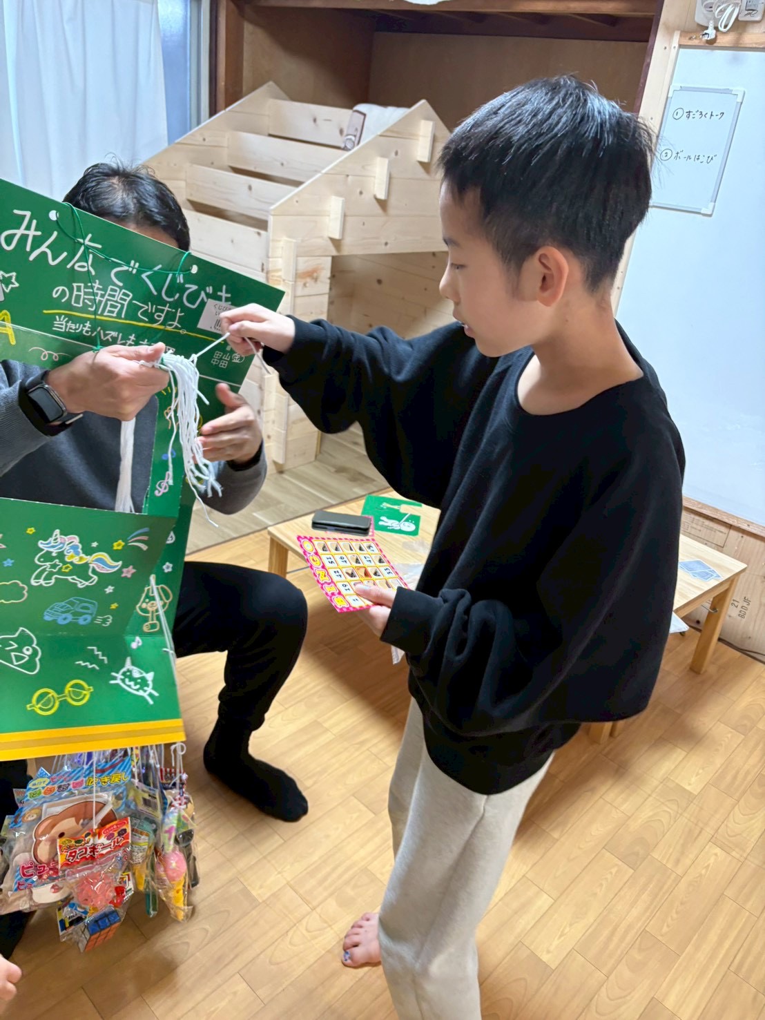 僕もビンゴだよ。お願いこのおもちゃが当たりますようにと、願いを込めて紐を引っ張る男の子。