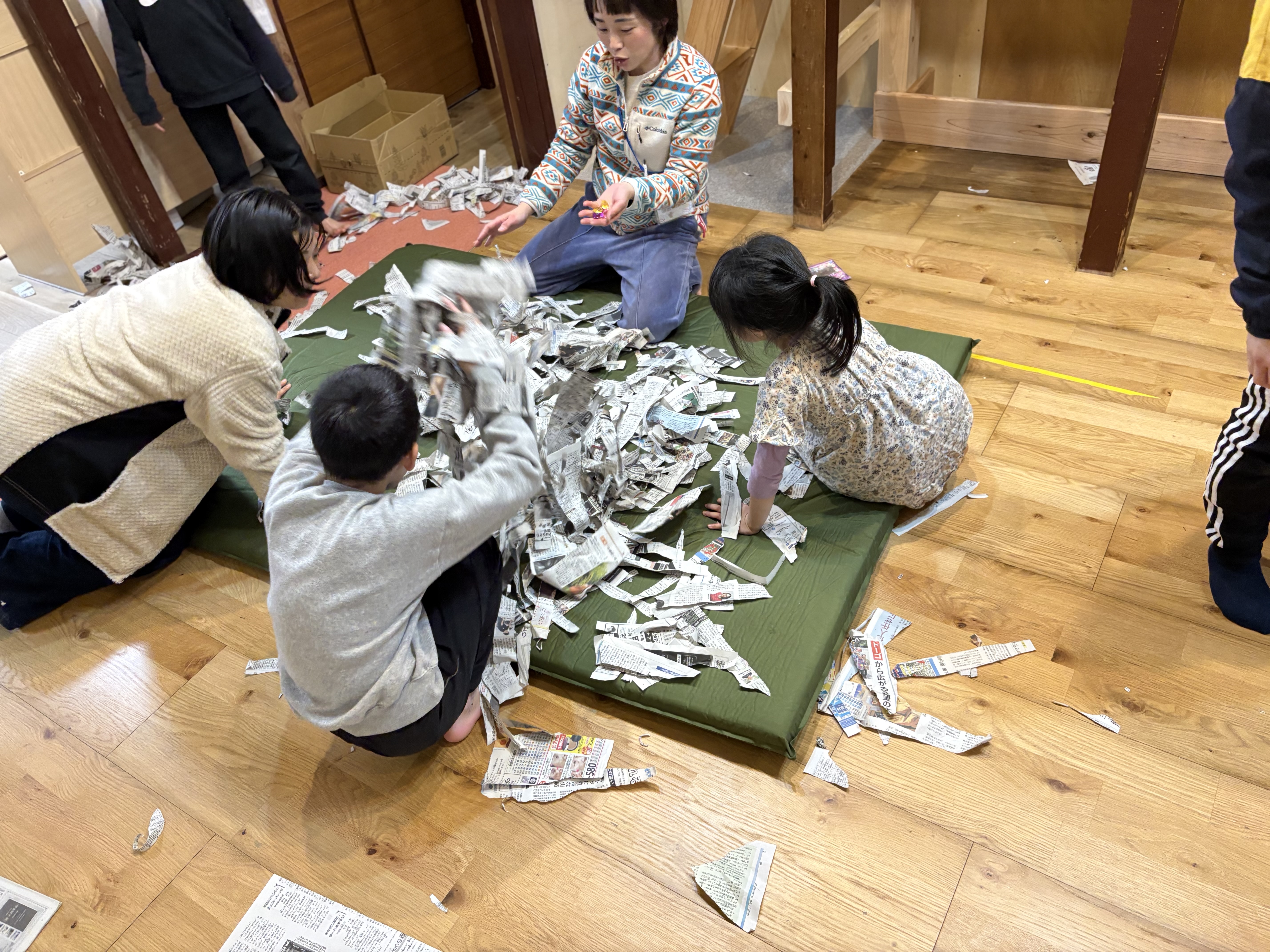 「あったー！！」伝説のビー玉を発見し、新聞紙の山から顔を出して宝石のように掲げる笑顔。