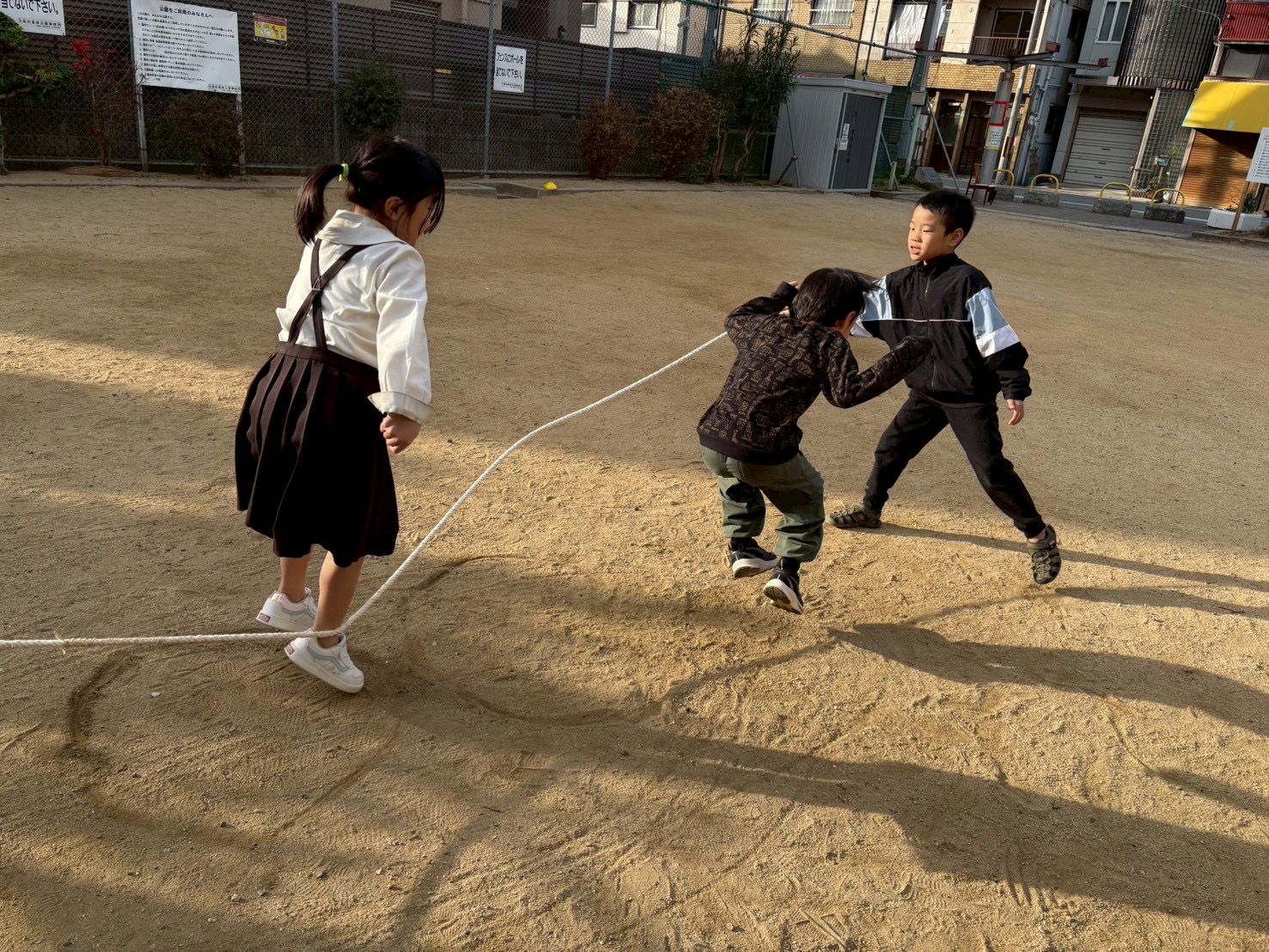 「リズムと笑顔の融合。」 縄が地面を叩く音に合わせて、満面の笑みで空中に舞う子どもたち。