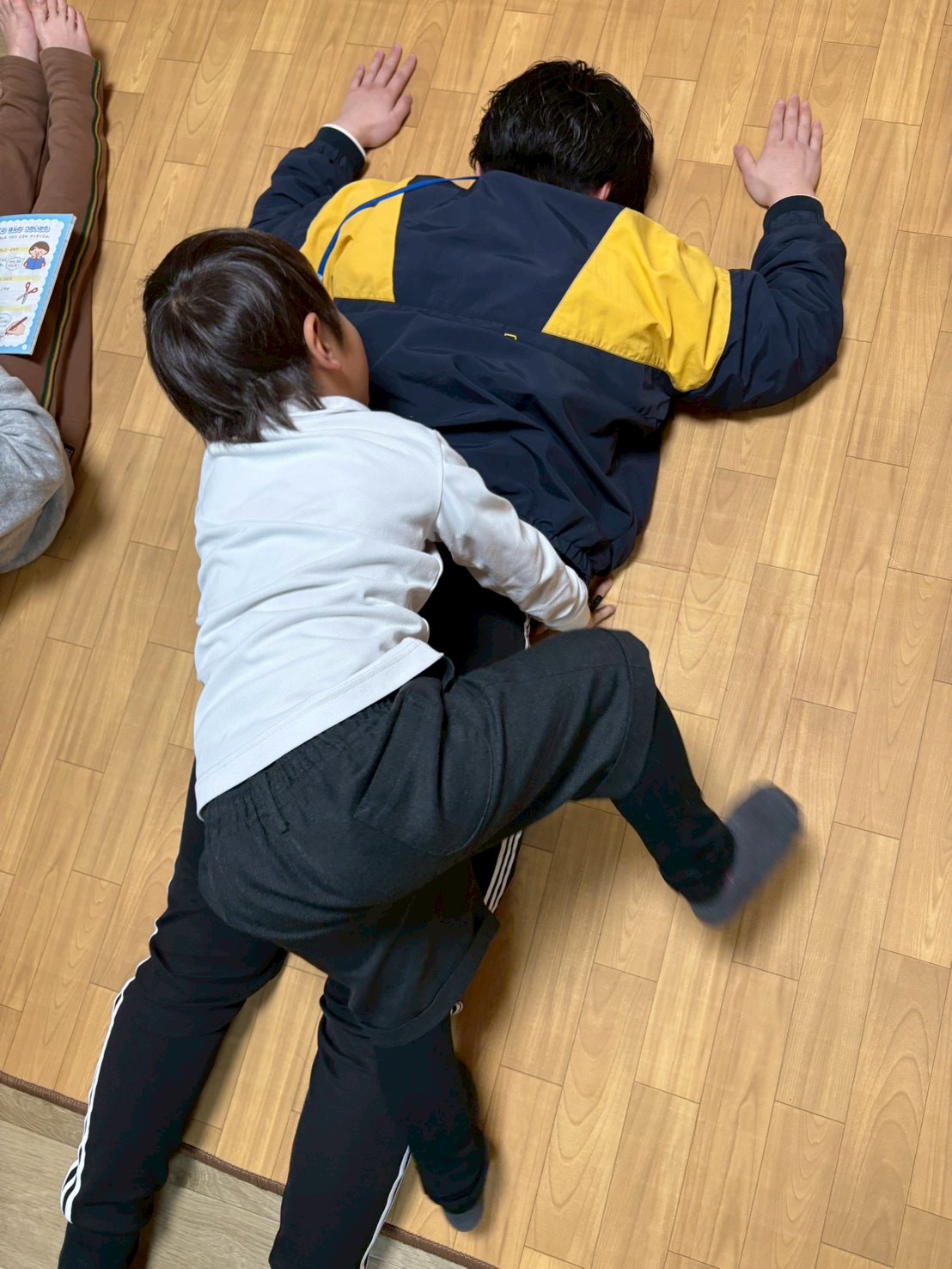 「ぐいーーーーっ！！」 全身の筋肉と体重を使って、大人をひっくり返そうとする子どもたちの必死な形相（体幹フル稼働！）。