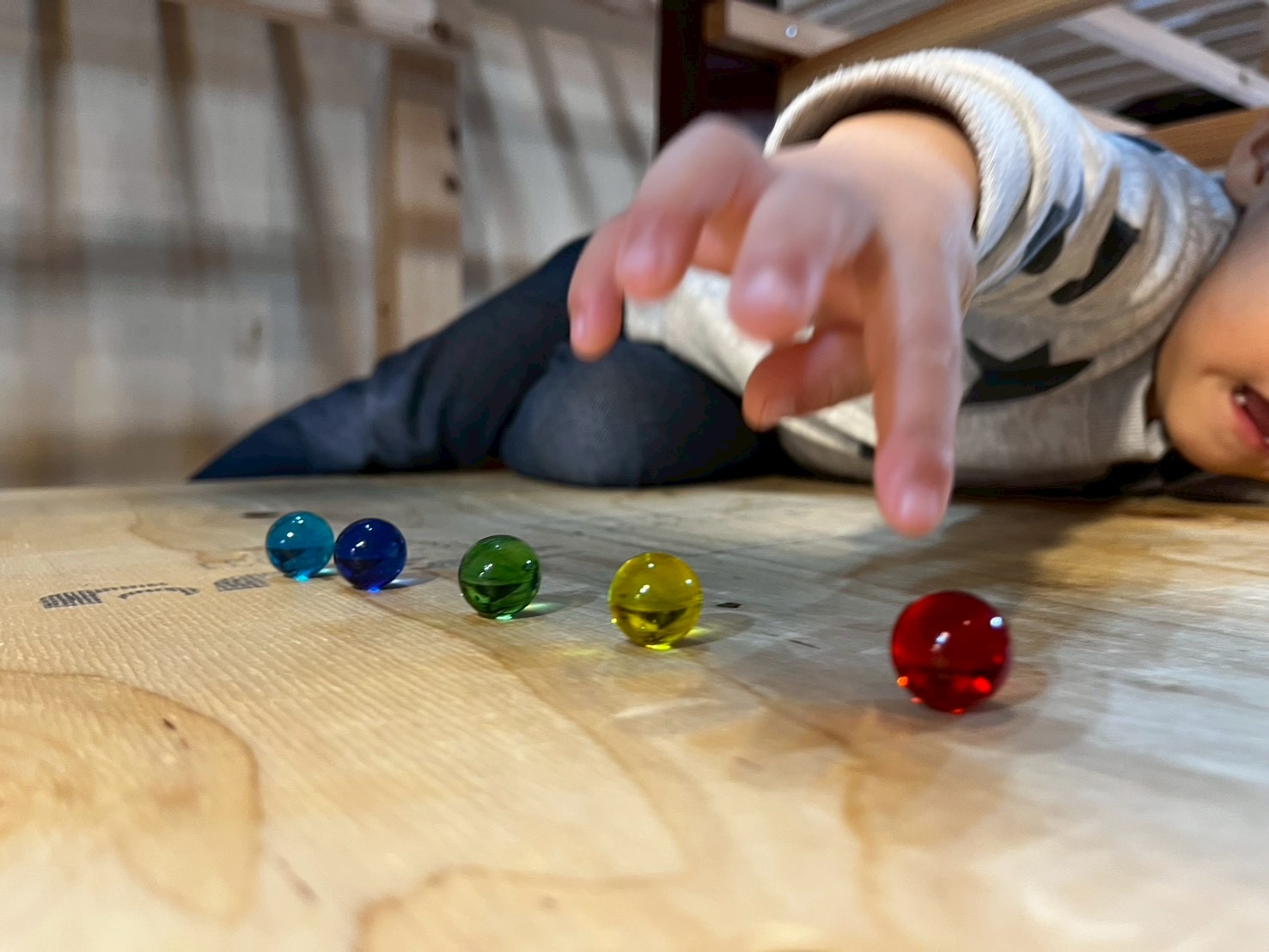 「木のぬくもりを触察。」 木工遊具の滑らかな曲線にそっと触れ、素材の質感を楽しんでいる穏やかな1枚。