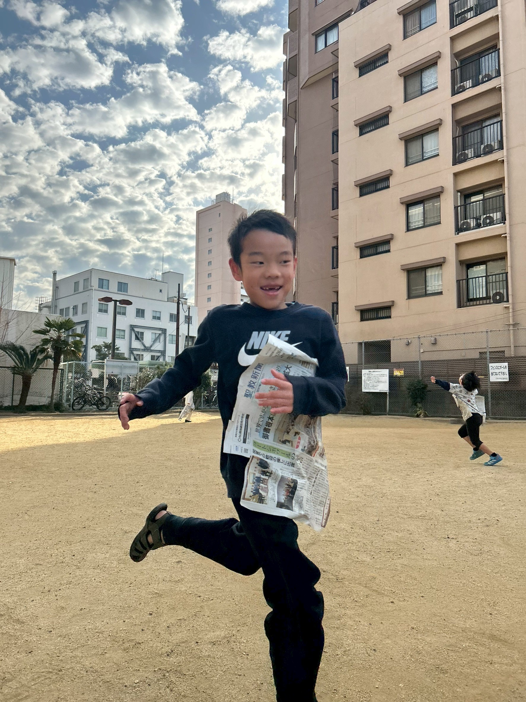 「新聞紙と一体化！」
スピードに乗り、新聞紙がピタッと胸に吸い付いたまま疾走する子ども。正しい前傾姿勢と、誇らしげな表情のアップ。