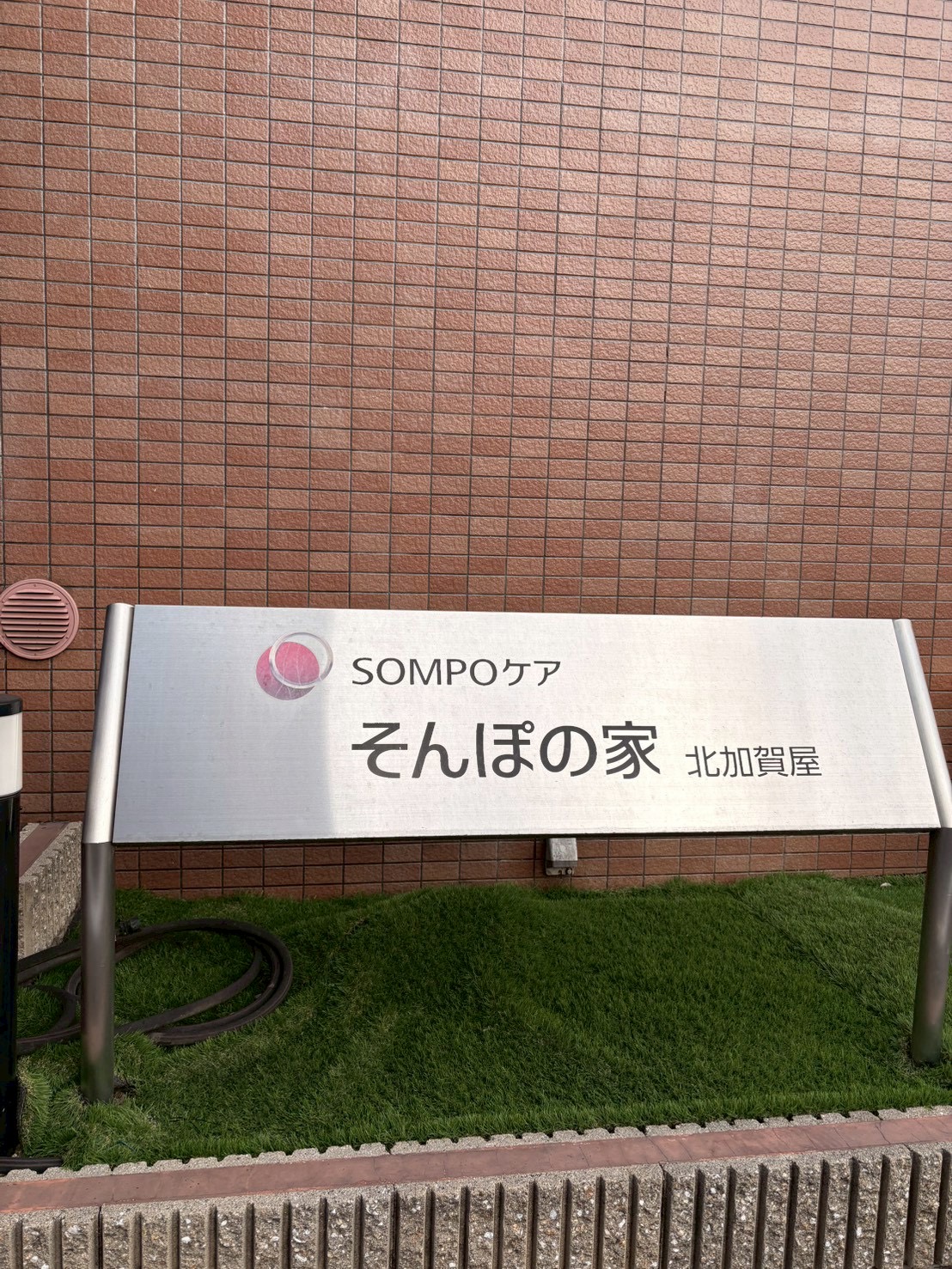 「はじめての場所、ワクワクの入場。」

「そんぽの家」の看板の前で、少し緊張しながらも期待に満ちた表情で一歩を踏み出す子どもたち。