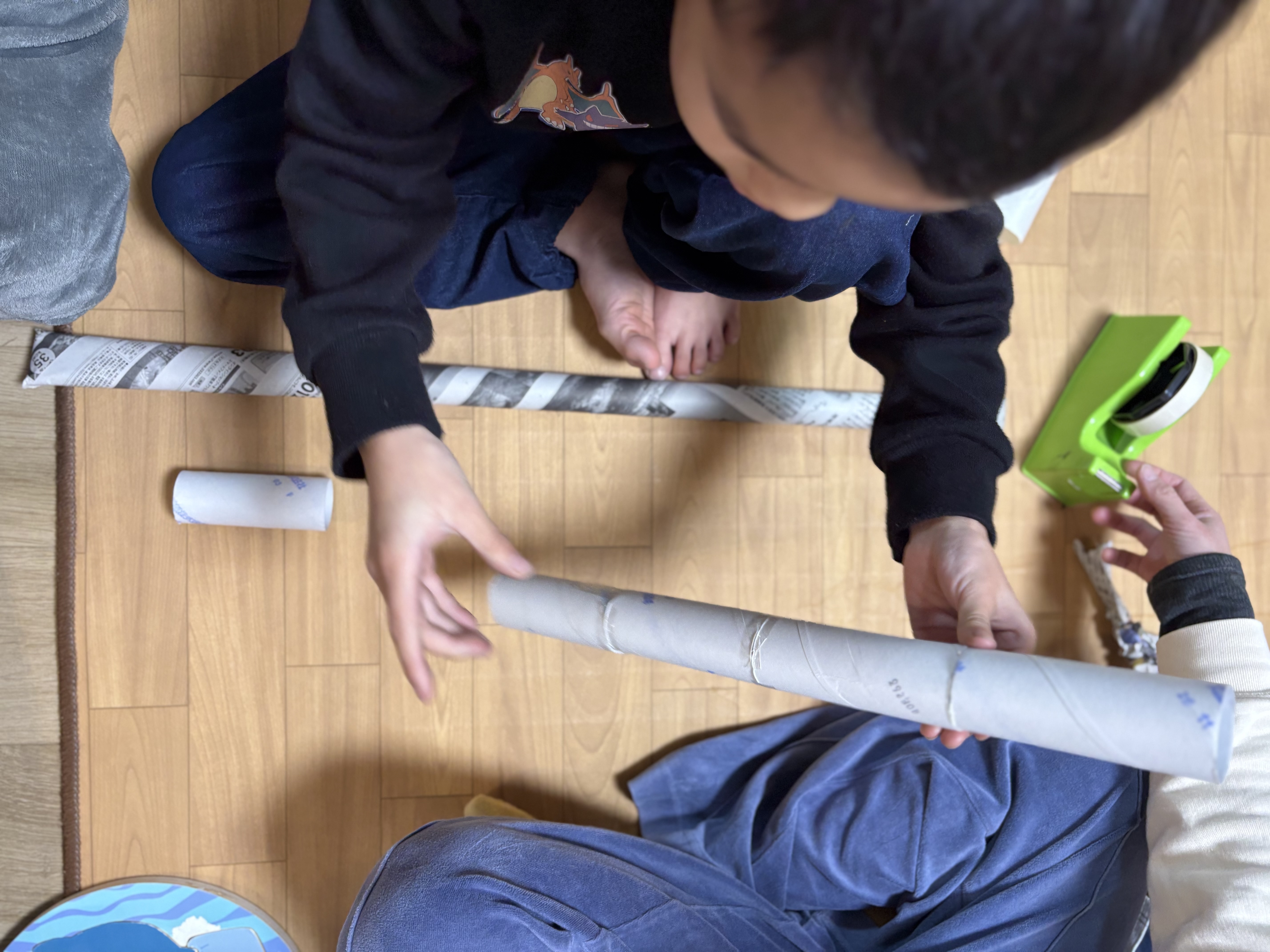 「押さえる手、貼る手。」
一人が新聞紙を押さえ、もう一人がテープを貼る。自然と発生した「二人三脚」の製作シーン。