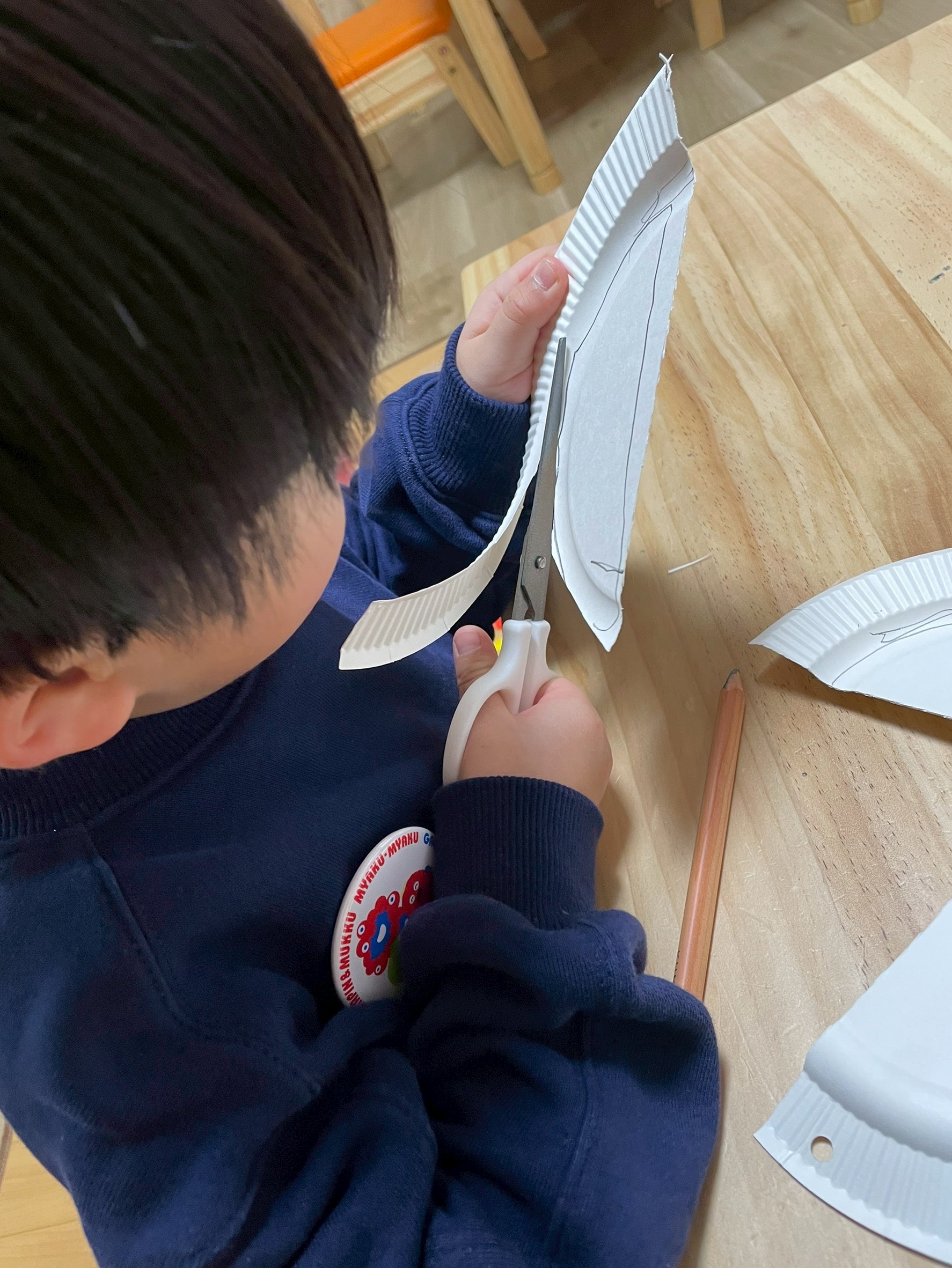 鉛筆で描いた線をハサミを使って、両手を器用に操る様子。