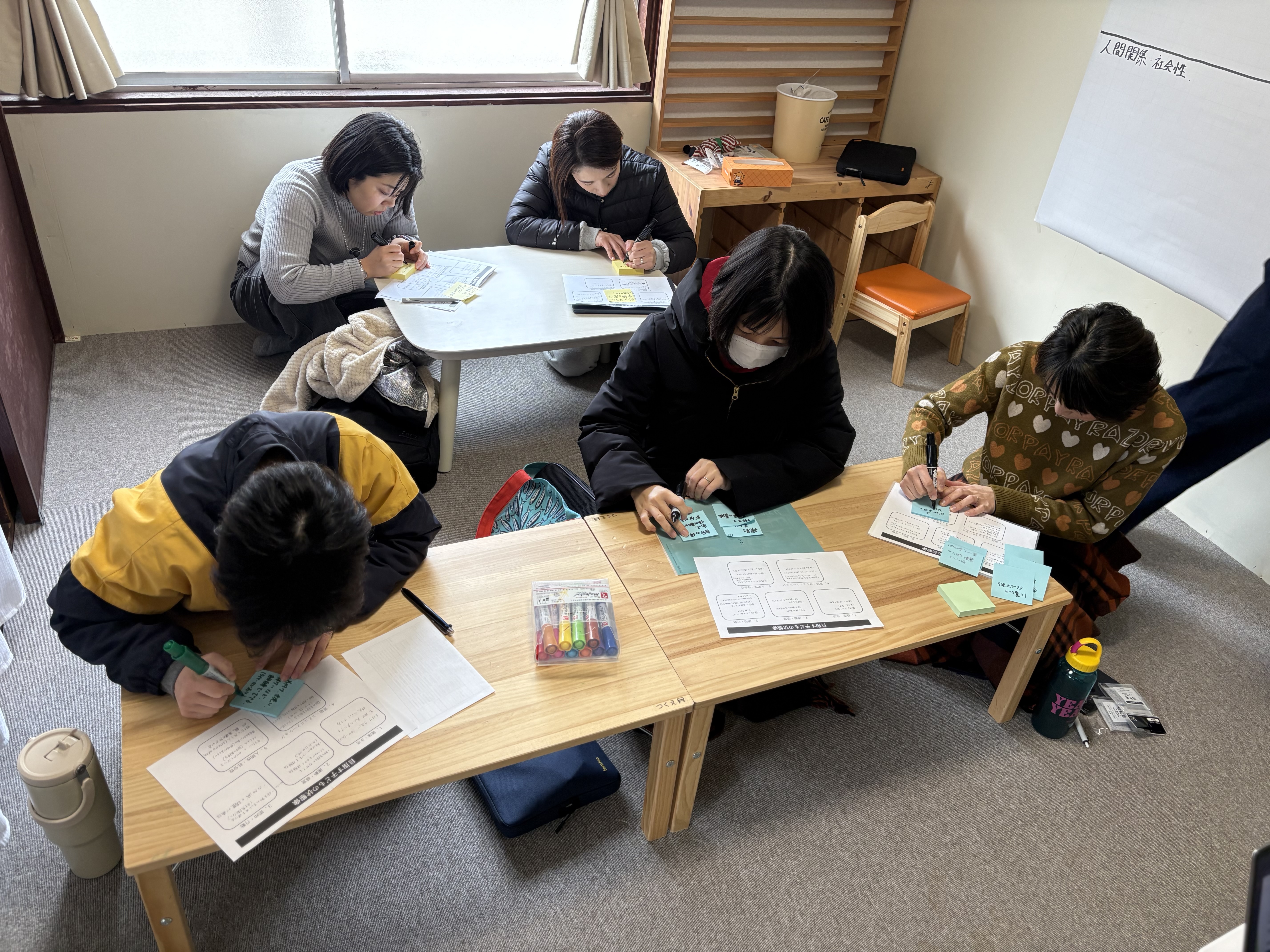 「想いを、言葉に変えるペン先。」

ポストイットに、担当するお子様の「具体的な笑顔の瞬間」を書き込むスタッフの手元。