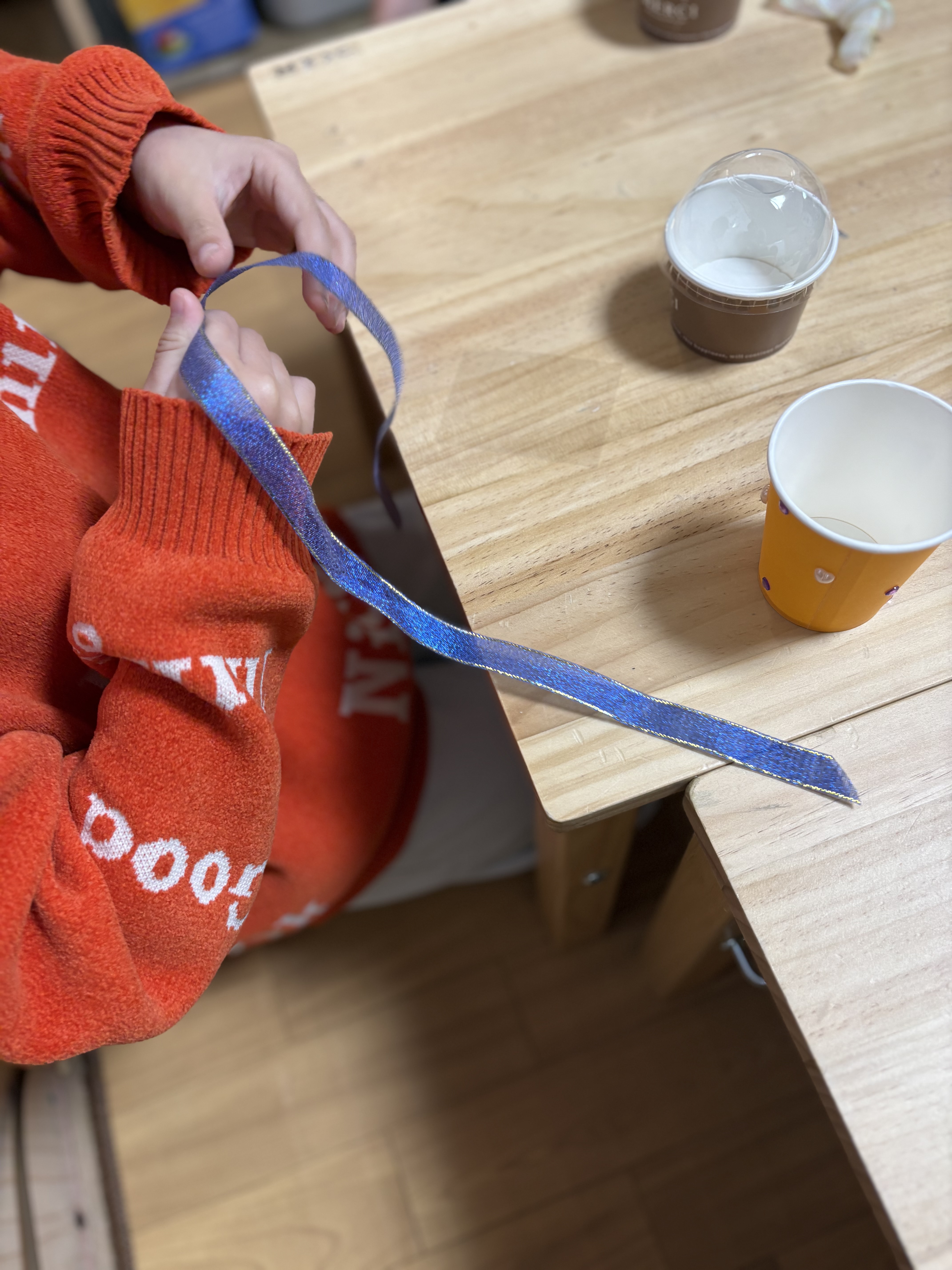 「ラッピングまで、自分の手で。」
袋にリボンを結ぶ。難しい「蝶々結び」に挑戦する、粘り強い指先の動き。