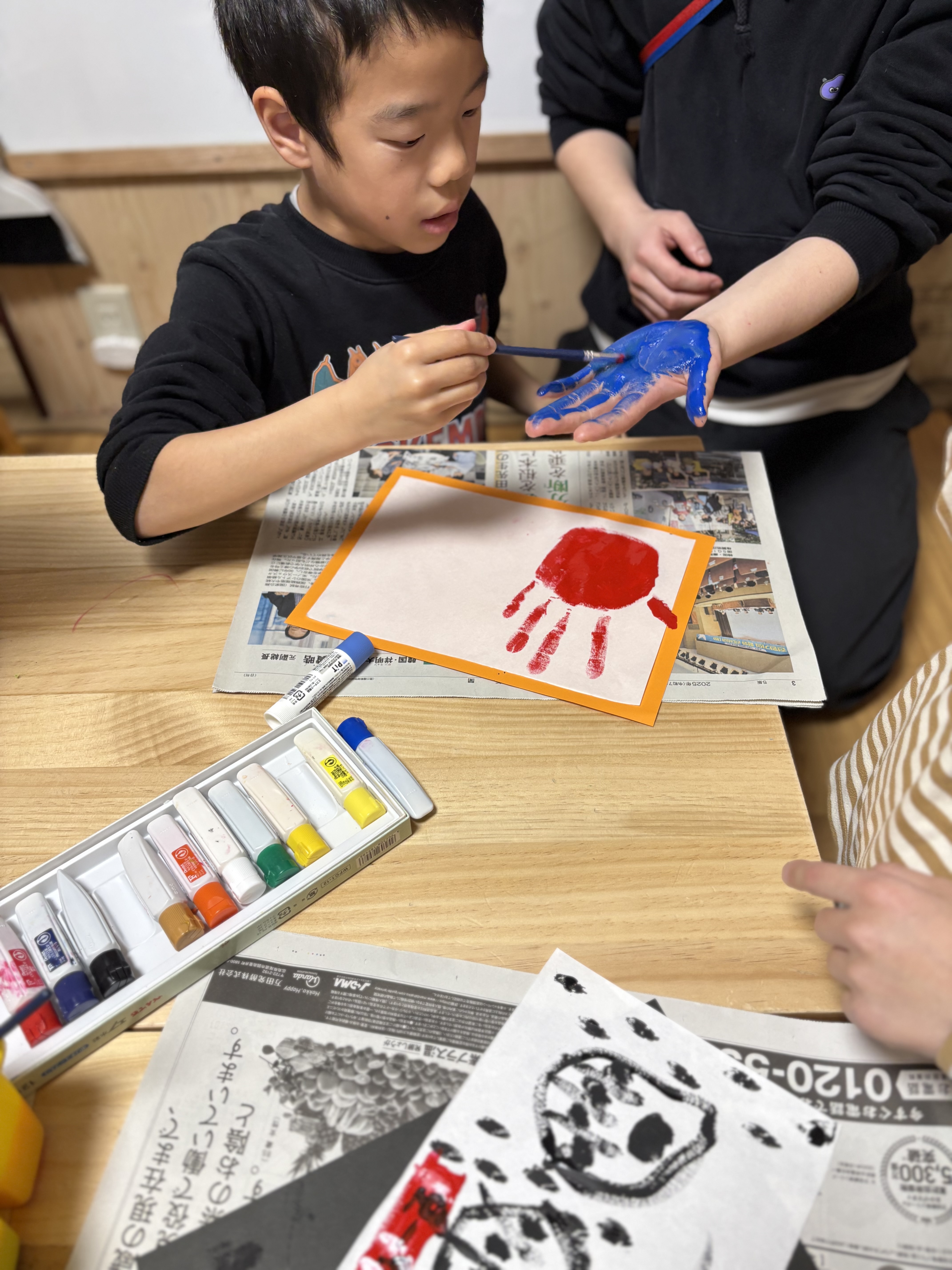 「色を重ねる、優しさの層。」
スタッフの指一本一本を丁寧に塗り分ける手元のアップ。力加減を調整しながら、隅々まで色を乗せていく「全集中」の指先。