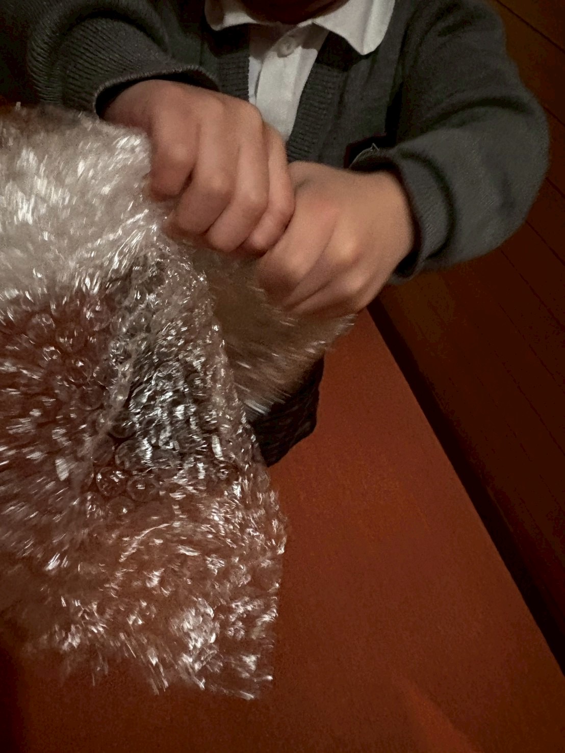 全身で包装紙を捻ることで、音が鳴り、なんだか気持ちがいいと喜ぶ姿。