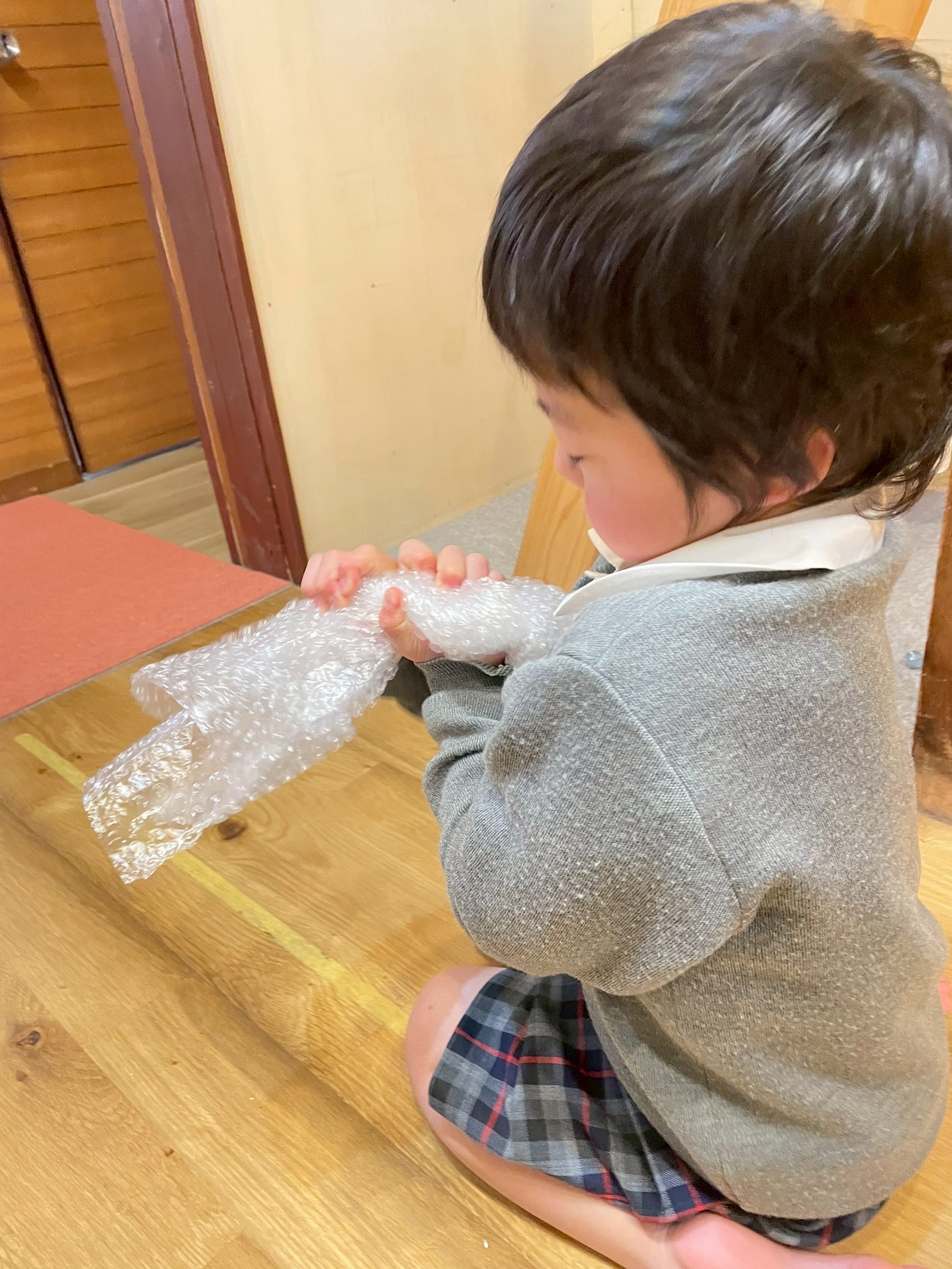 プチプチとなる音をたくさん出すためには、全身を使うことが大切だと研究する男の子。
