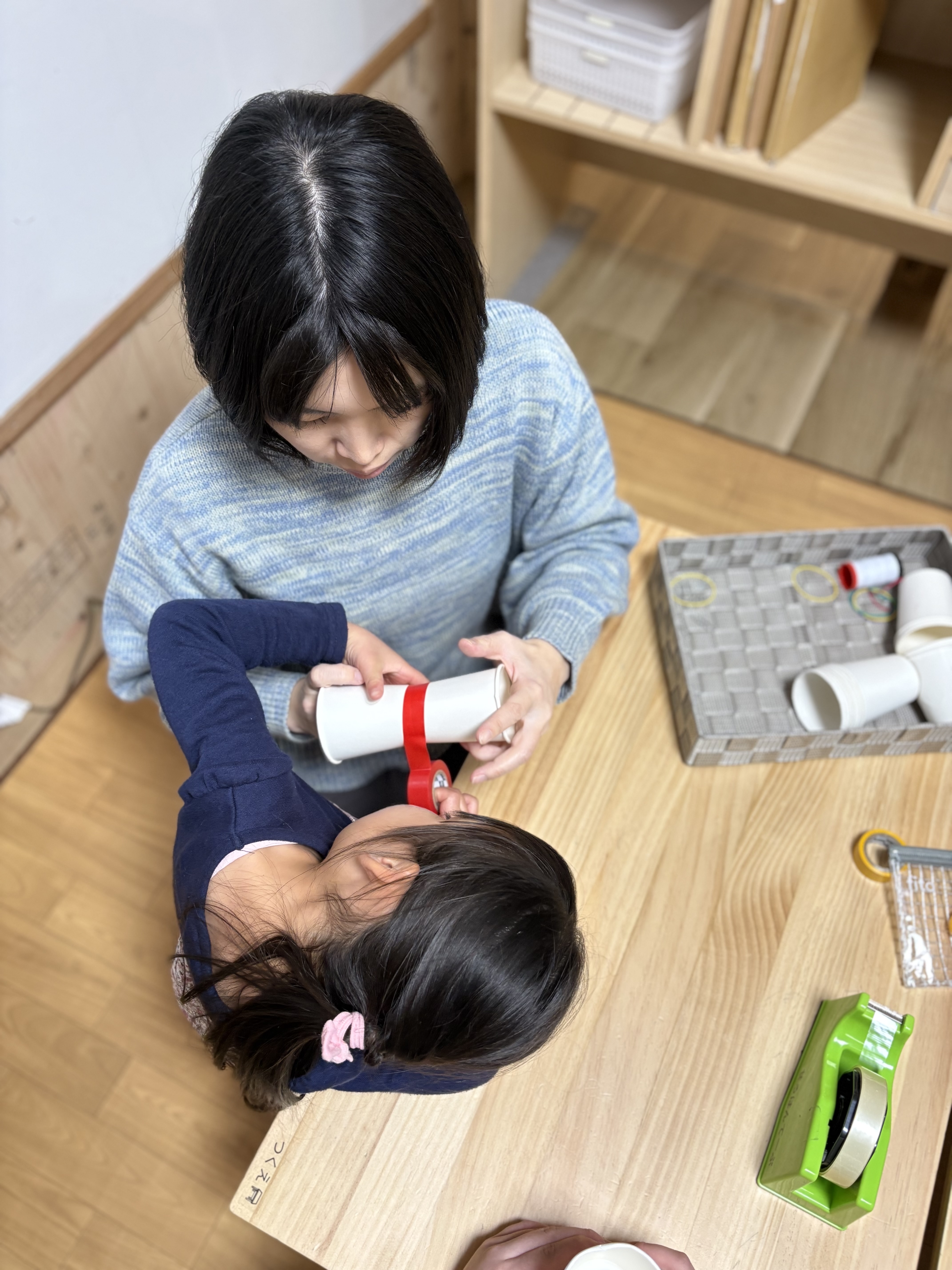 「背中合わせの、ドッキング。」
二つのコップを合わせ、テープで慎重に固定する手元のアップ。左右のバランスを意識する「空間認知」の始まり。