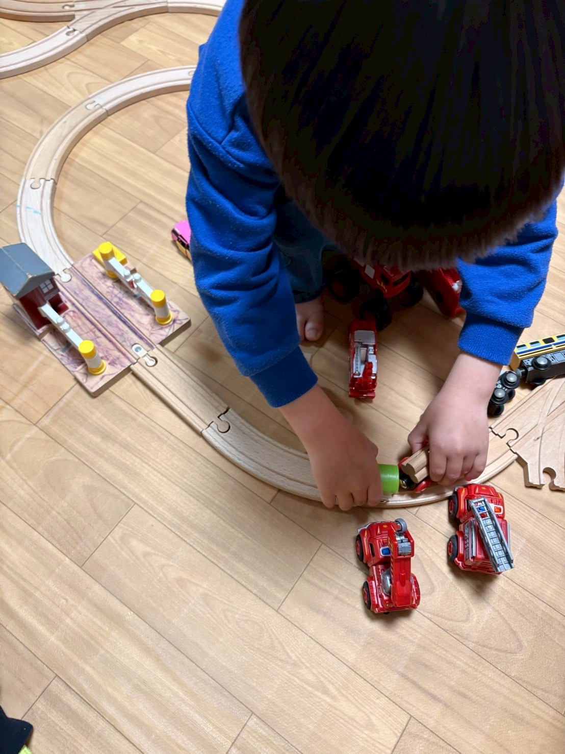 「線路は続くよ、心の整理まで。」
木のレールをパズルのように組み合わせ、自分の世界を広げていく手元のアップ。木の柔らかな質感が伝わる1枚。