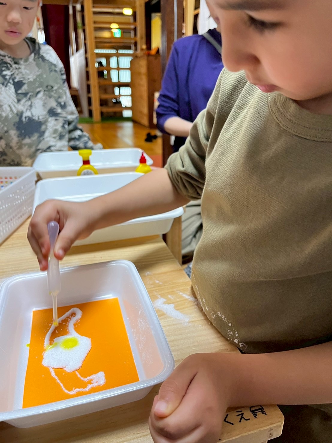 「色を混ぜる、真剣な手元。」

塩と絵の具をスプーンで混ぜ混ぜ。色がじわっと広がっていく様子を見つめる鋭い観察眼。