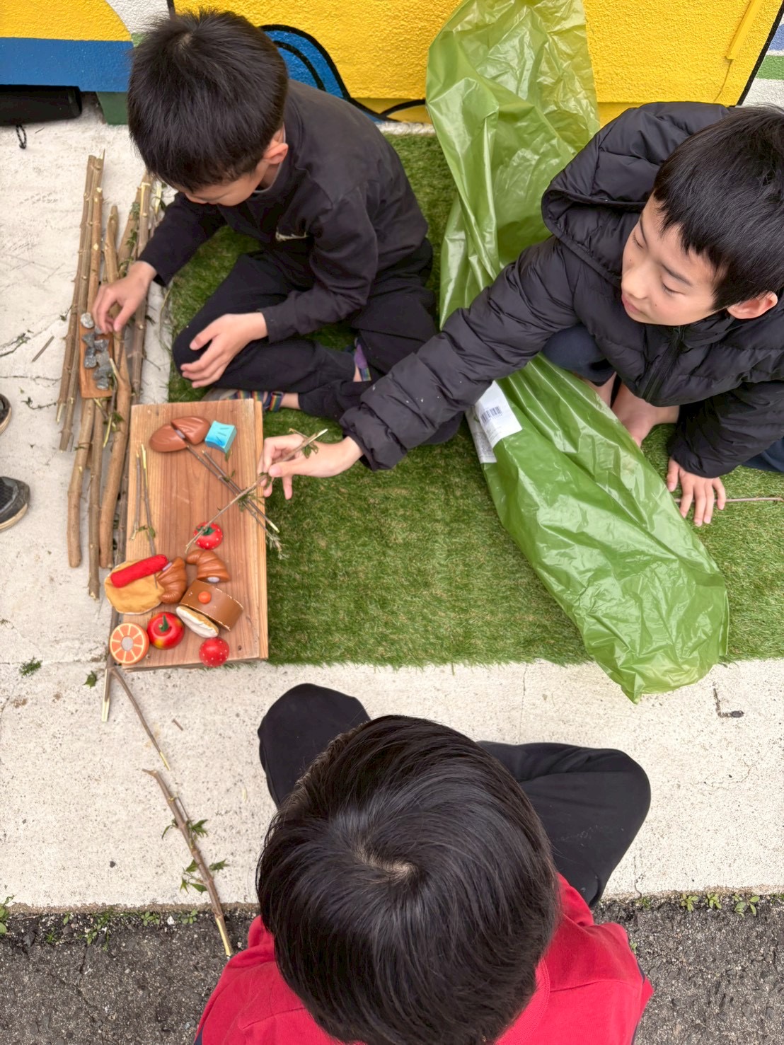 「ちぐはぐアートと、小さなキャンパー。」

独創的な壁画を背景に、芝生でくつろぐ子どもたち。アートと遊びが完全に融合した引きの構図。