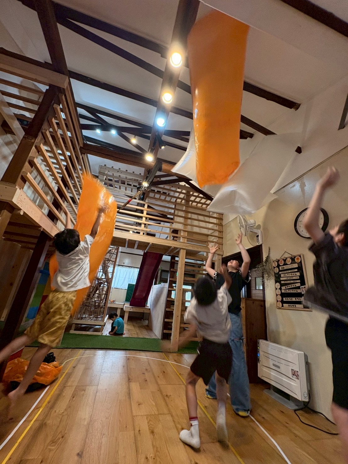 「バルーンの波がやってくるぞー!」
スタッフが揺らす巨大なバルーンの波に向かって、子どもたちが「キャー!」と嬉しそうに身をかがめる躍動感のあるカット。