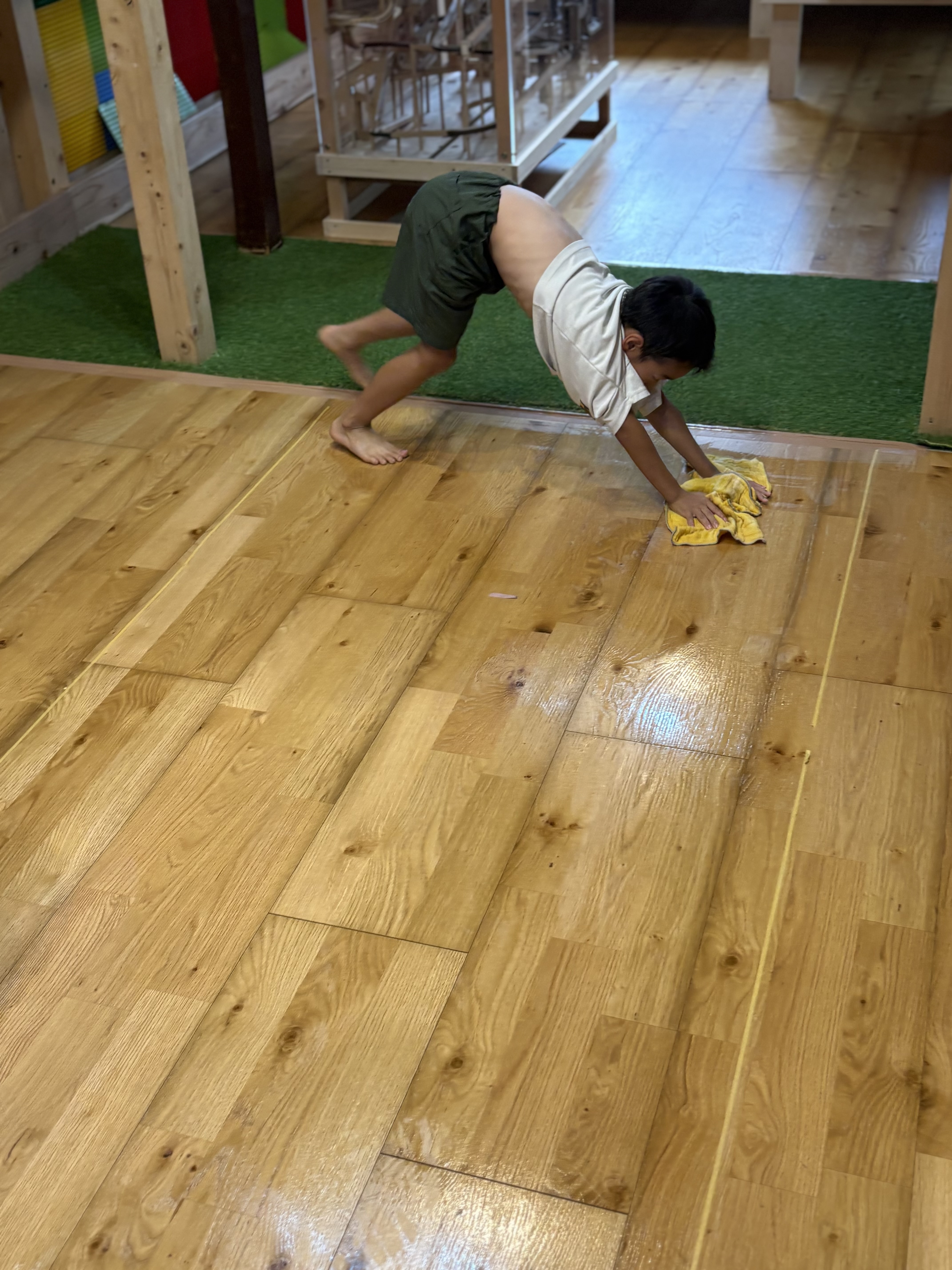 「隅っこも見逃さない!小さな手で丁寧に柱の周りを拭く優しさ」
木工遊具のすき間や柱の根元など、細かい部分にまでそっとぞうきんを滑らせて汚れを取り除く、場所を大切にするまなざしの1コマ。