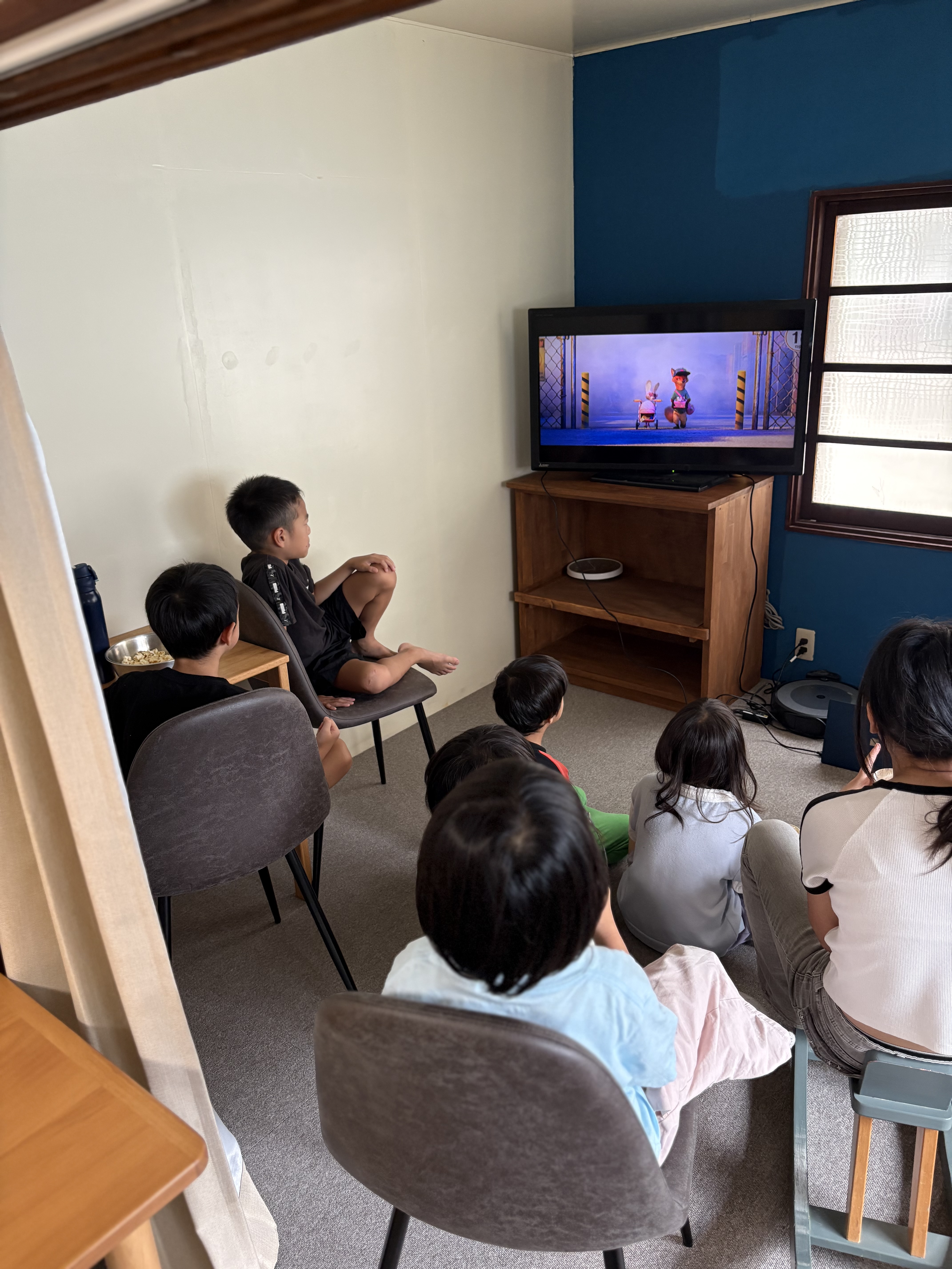 「画面に全集中！スクリーンを見つめる真剣な子どもたちの横顔」
薄暗い部屋の光の中で、スクリーンをまっすぐに見つめる子どもたちのキラキラした瞳。