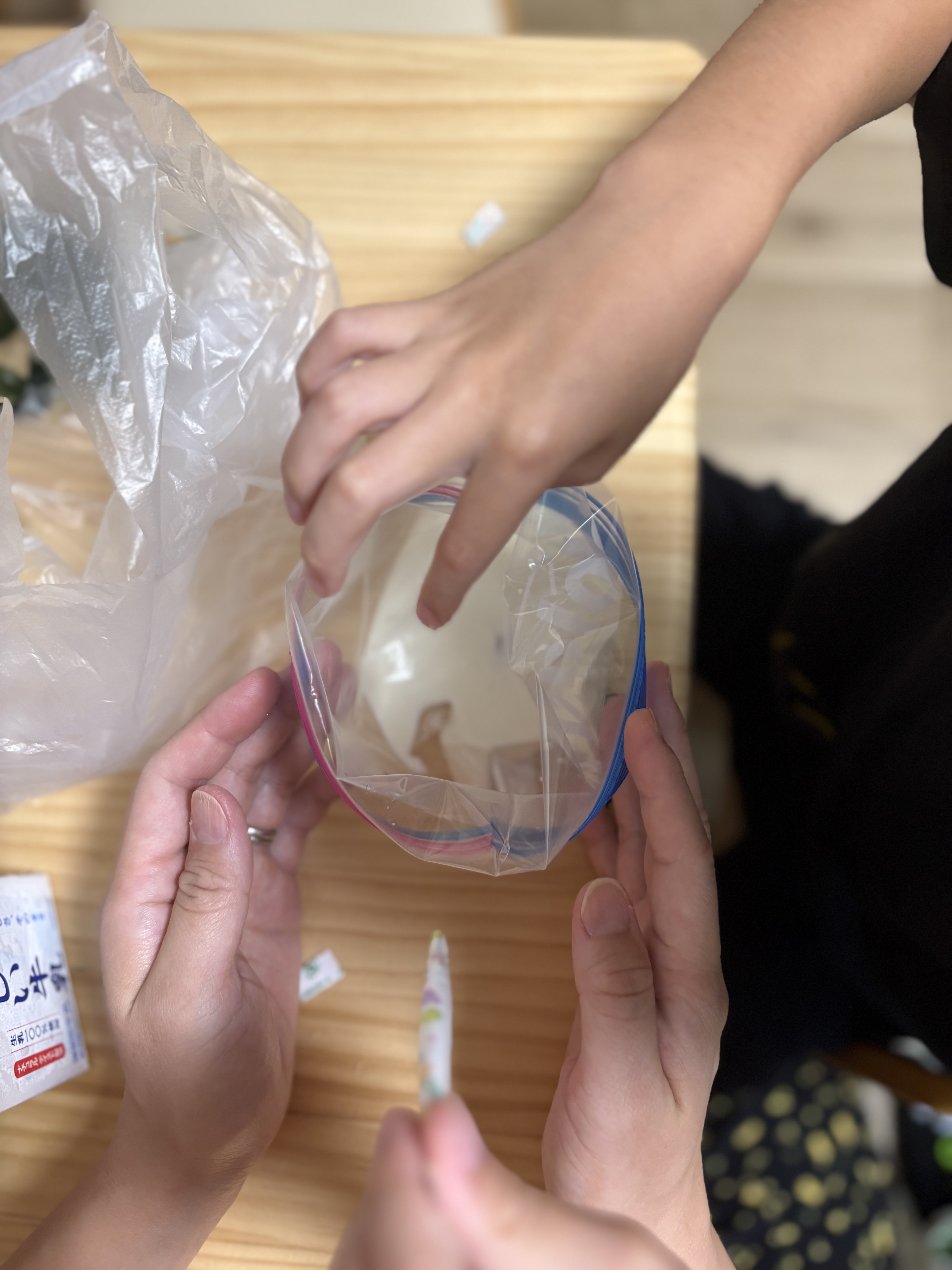 「氷とお塩を入れて準備OK!『冷たさ対策のタオルもしっかり巻いて』」
大きな袋に氷と塩を入れ、材料バッグをセットして固く結ぶ準備完了のカット。