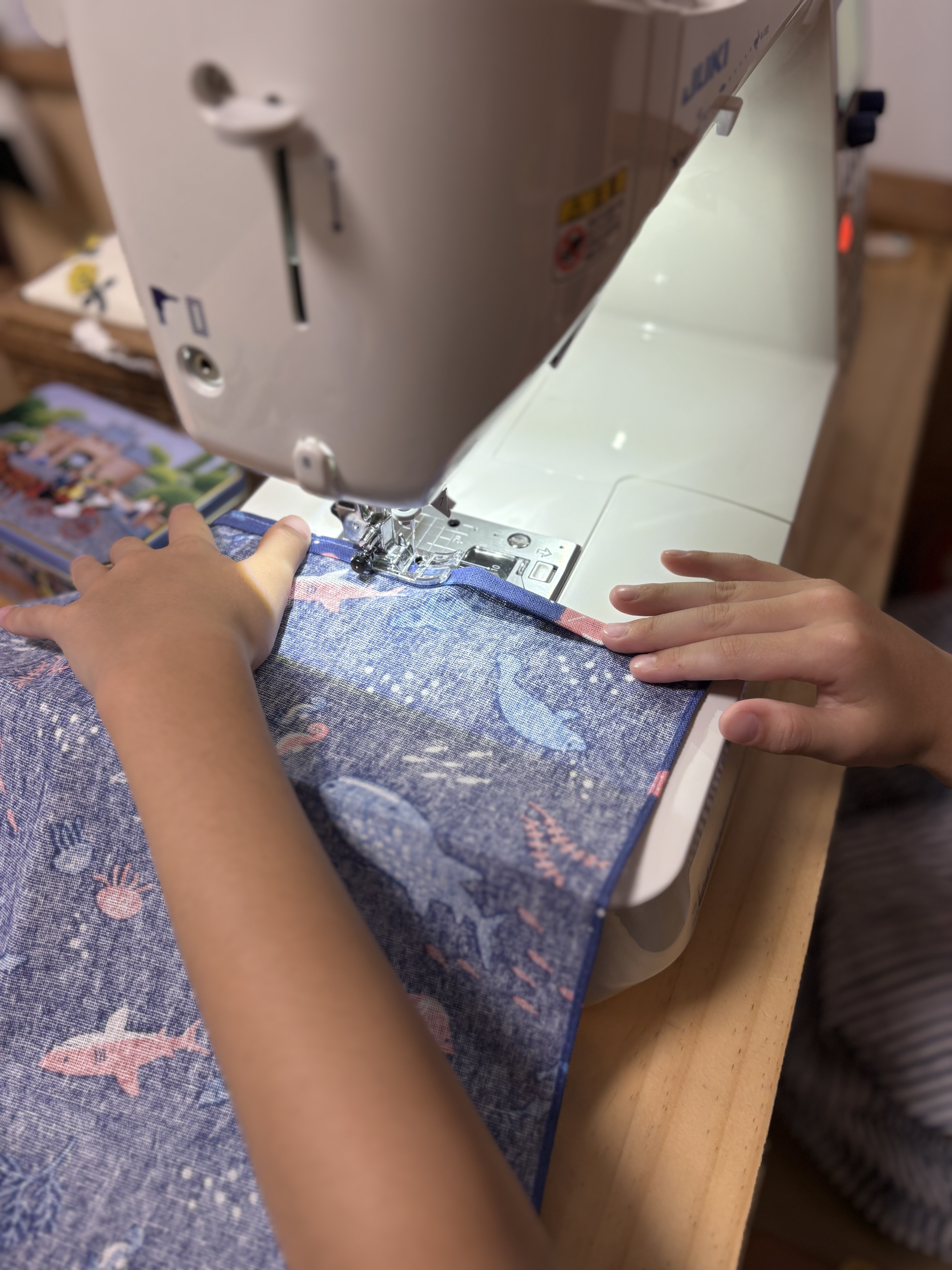 「『針がちょっと怖いな…』ドキドキしながらミシン台へ」
初めてのミシンに少し緊張気味で、手元をじっと見つめる挑戦前の真剣な表情。