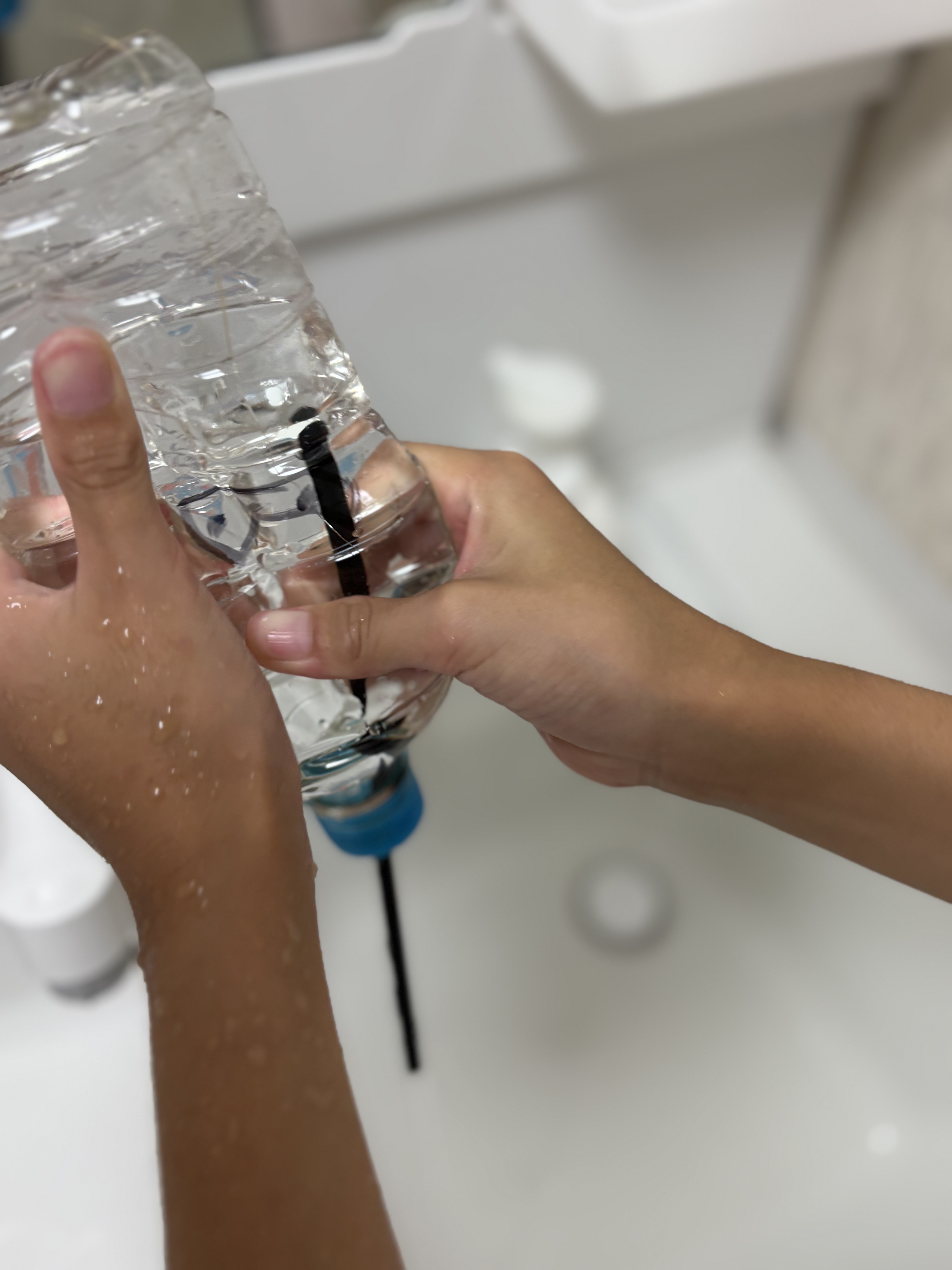 「『お水をたっぷり注いで…』いよいよ最終セット!」
ボトルになみなみとお水を注ぎ入れ、特製キャップをキュッと固く閉める準備ショット。
