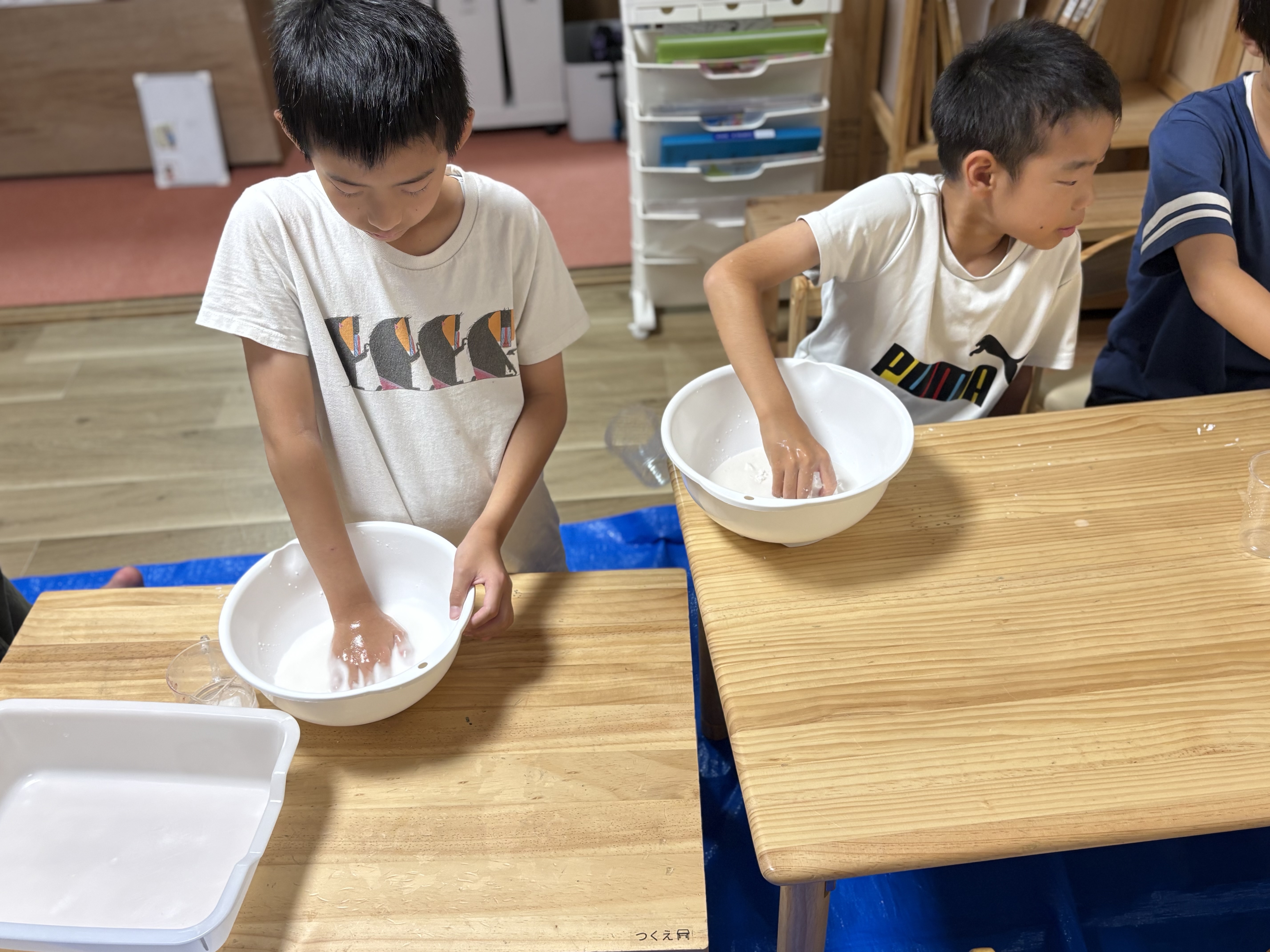 「お友達と見せ合いっこ!『僕のもトロトロになったよ!』」
隣のお友達とボウルを並べ、「固まる?」「溶ける!」とお互いの変化を観察し合う温かい1コマ。