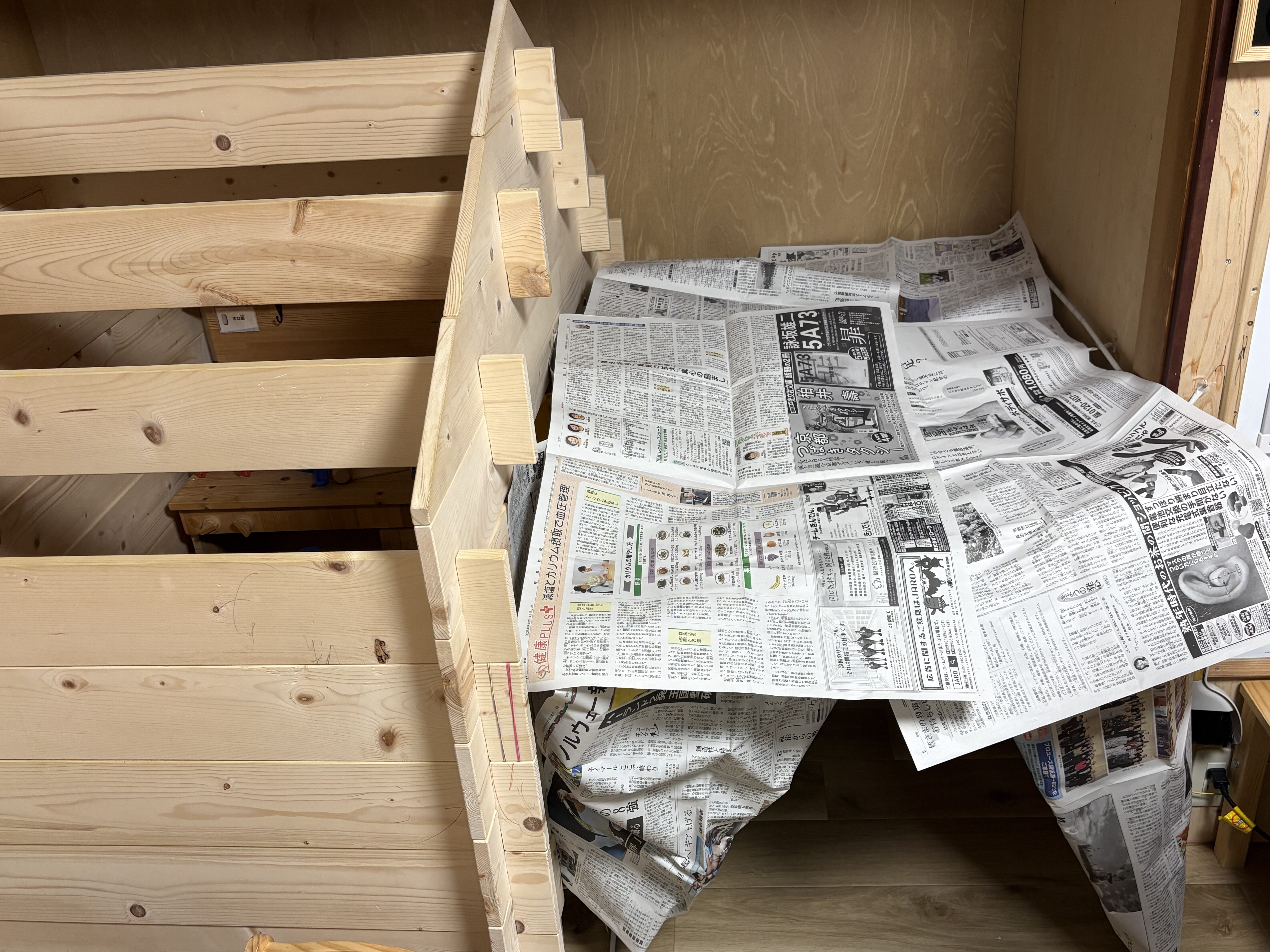 「部屋いっぱいに立ち上がった立派な新聞紙ハウスの全景」
みんなの協力で作り上げた大型の新聞紙ハウスの引きショット。