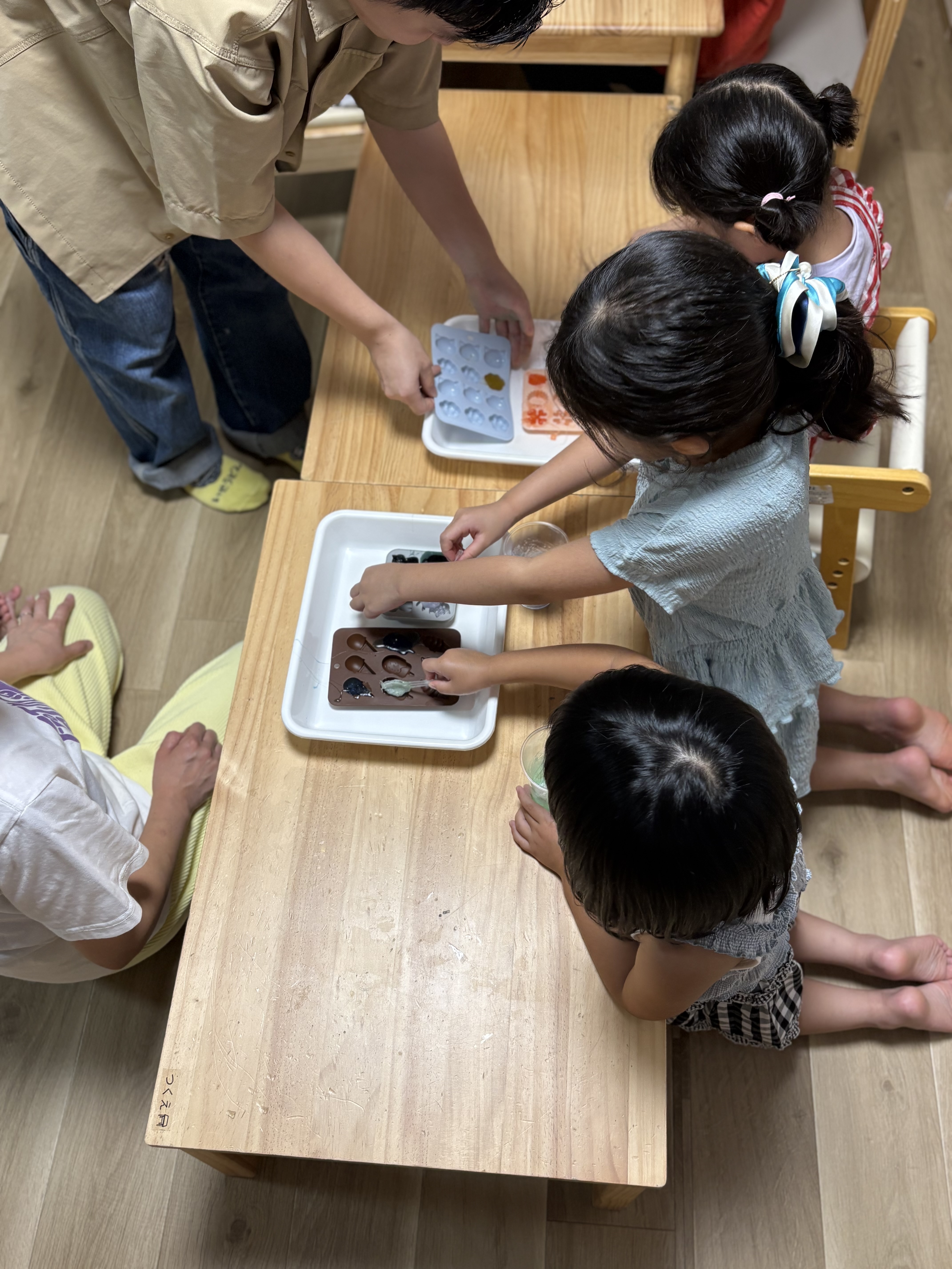 「『この青と緑を混ぜたら綺麗な海みたいになるかな？』色合わせに真剣な表情」
色パーツを手にとり、重ねたり光に透かしたりして色の組み合わせをじっくり考える表情。