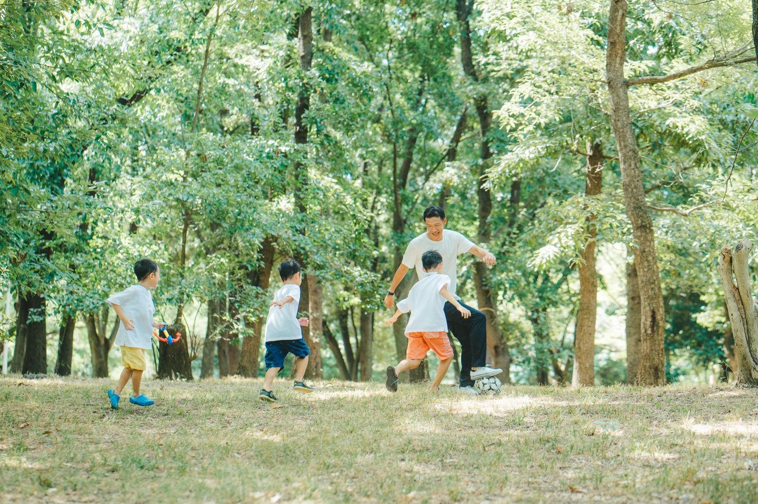 子ども達と一緒にサッカーを楽しんでいる様子。3人の男の子たちが、代表のボールを必死で奪いにいく瞬間。