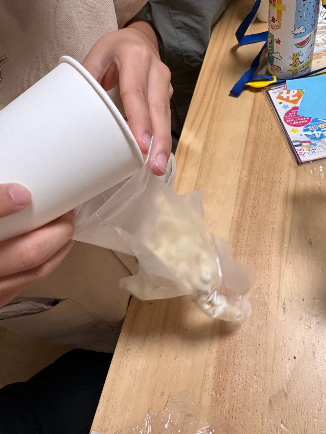「『あつあつのポップコーンがいっぱい!』紙コップへ取り分ける手元」
香ばしい匂いあふれる出来立てのポップコーンを、自分の紙コップへ丁寧にすくい入れるクローズアップ。