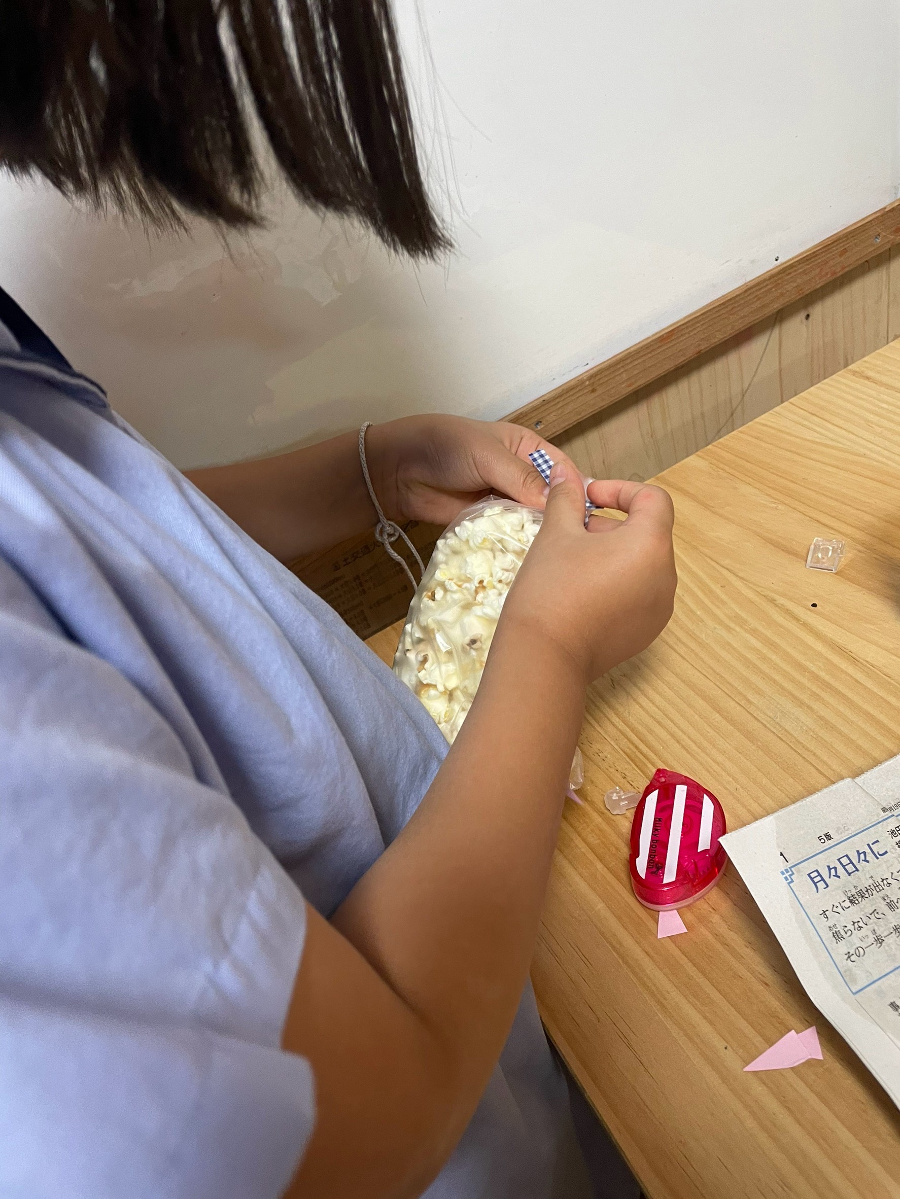 「『紙コップのふちを使ってスーッ!』ナイスアイデアの流入テクニック」
紙コップの先端を少し潰して細くし、手袋の細い指先へポップコーンをスムーズに流し込んでいる技ありショット。