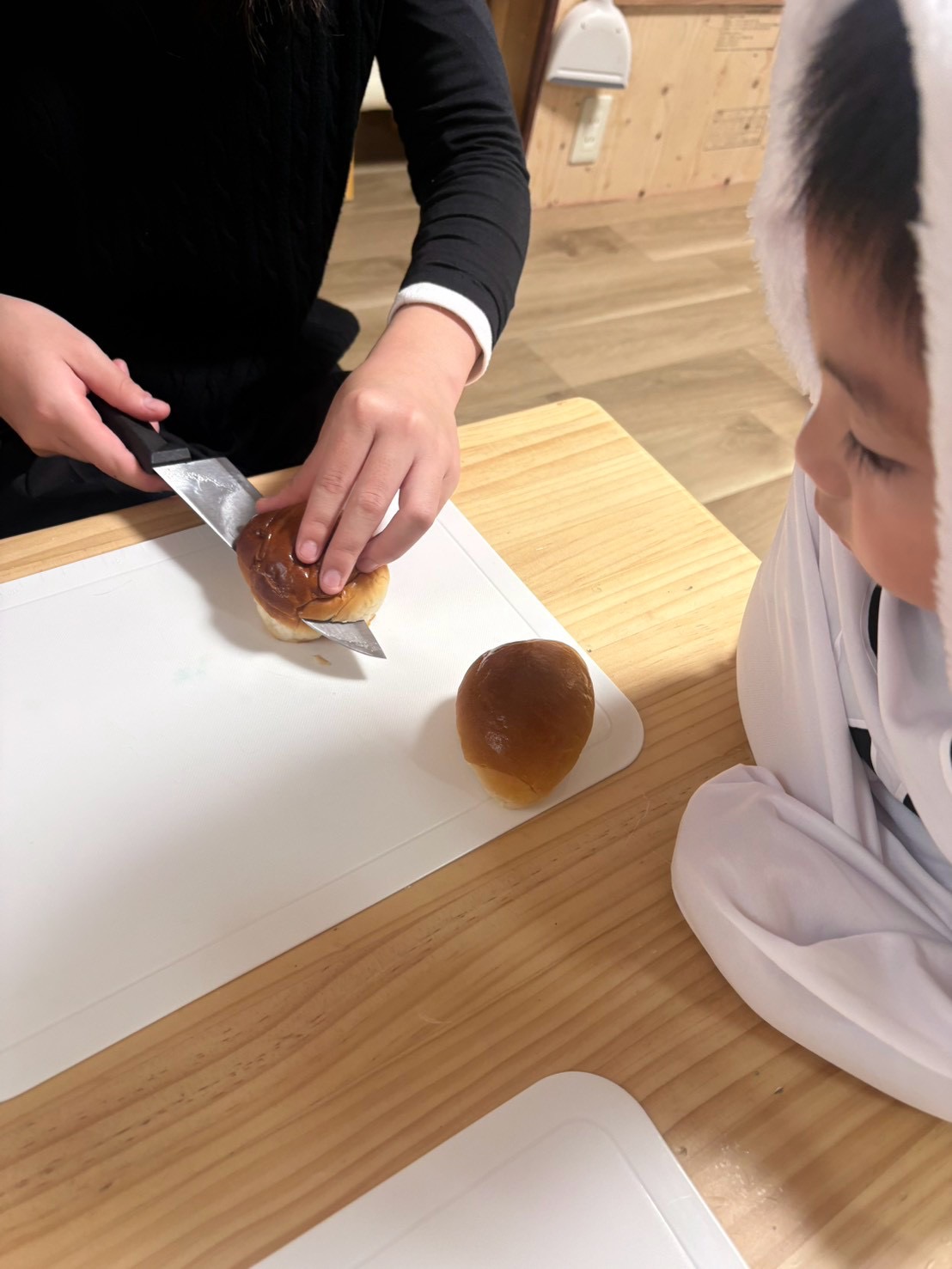 「『指先に全集中…トントン!』パンに切れ込みを入れる包丁使い」
包丁を両手でしっかり握り、パンの側面に慎重にお口の切れ込みを入れていく真剣な手元クローズアップ。