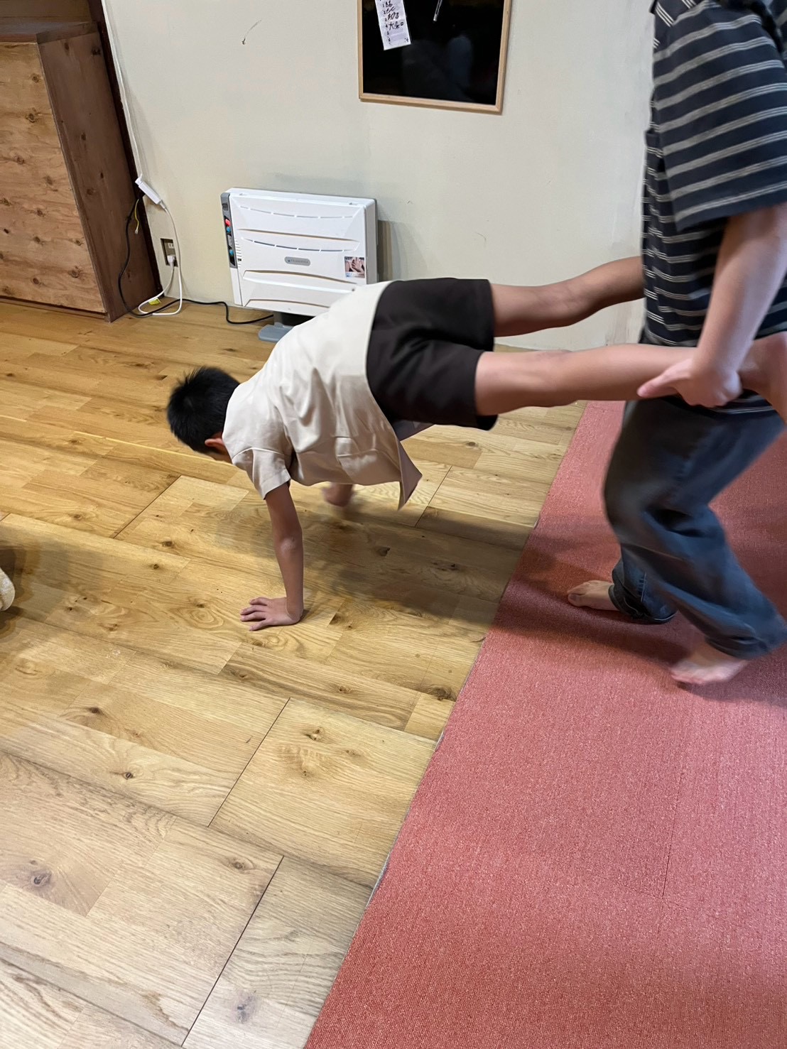 「『手をついて準備OK！』スタッフと呼吸を合わせるスタートカット」
床に両手をつき、スタッフが足を持ち上げてピシッと体幹を保つ手押し車のスタート構えショット。
