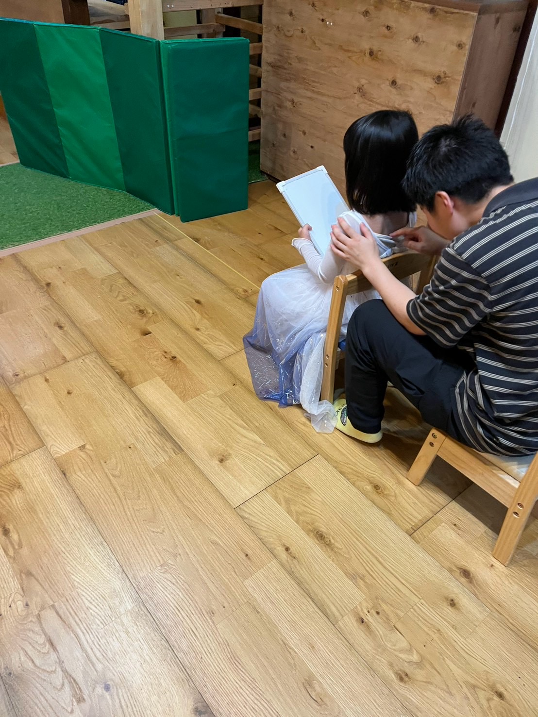 「『僕の背中に届いたのは…コレだ!』ホワイトボードに向かう誇らしげな後ろ姿」
一番前の子どもが真剣な表情でホワイトボードに向かい、ペンをとって一気に図形を描き込む1コマ。