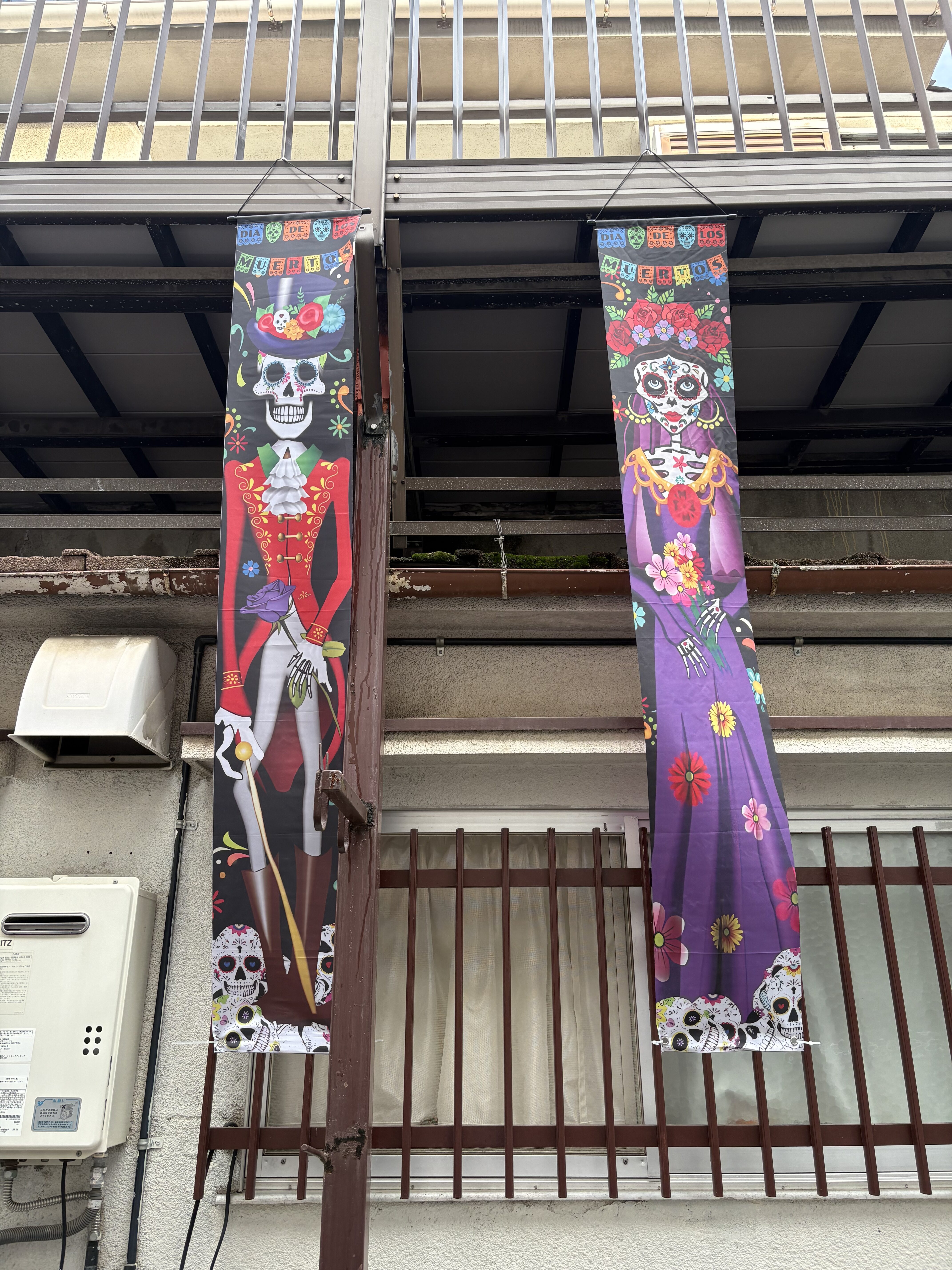 「『インパクト抜群!』ドクロの大型タペストリー設置完了」
窓際や外壁にどーんと飾られた大迫力のドクロタペストリーと、それを見て「すごい!」と目を丸くする子どもたち。