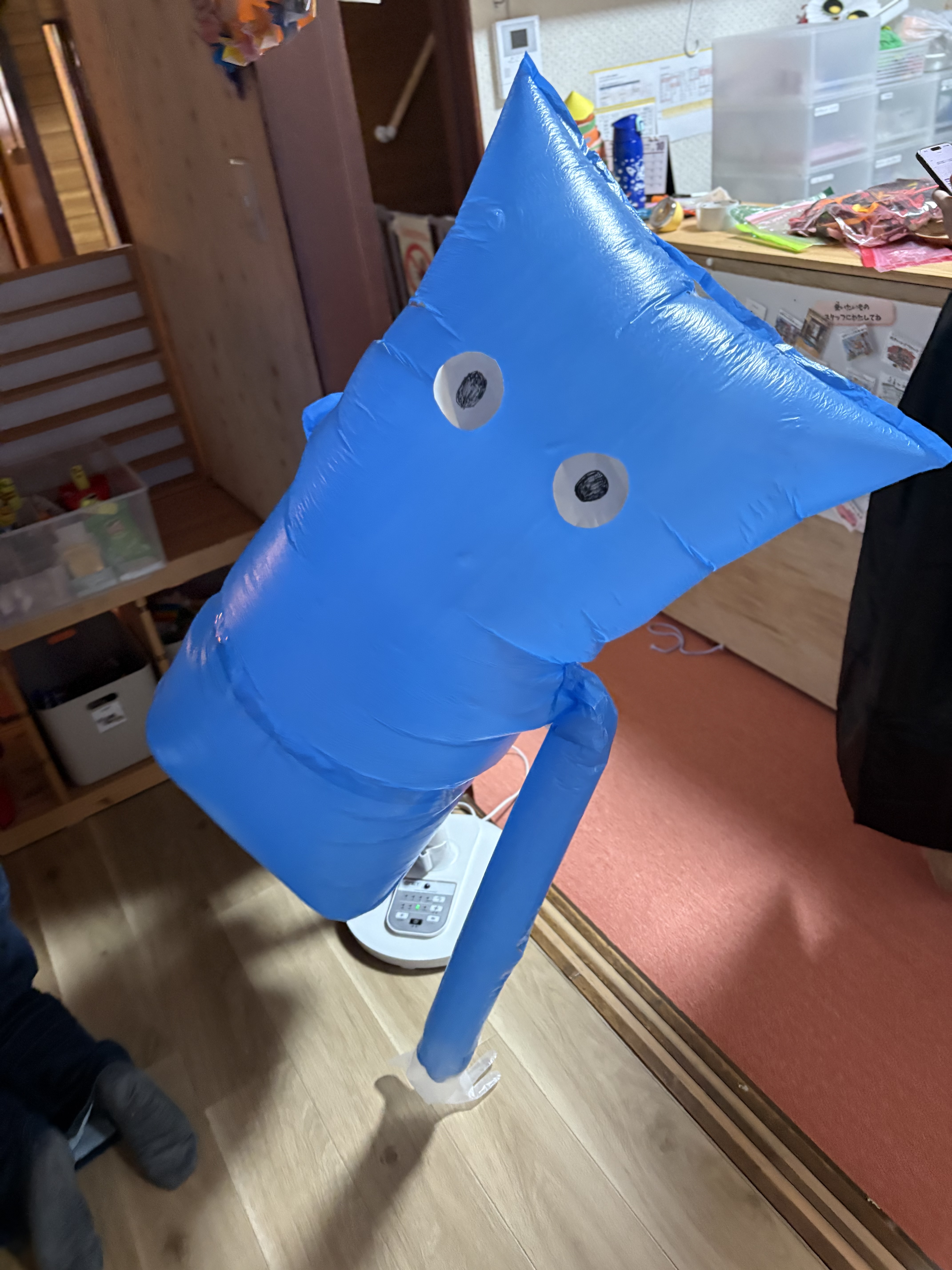 「『なにこれー！でっかーい！』謎の青いエアバルーン人形登場」
ぬりかべのような不思議でビッグな青いエアバルーン人形が突然現れ、「うわぁ！」と目を見開いて大喜びする子どもたち。