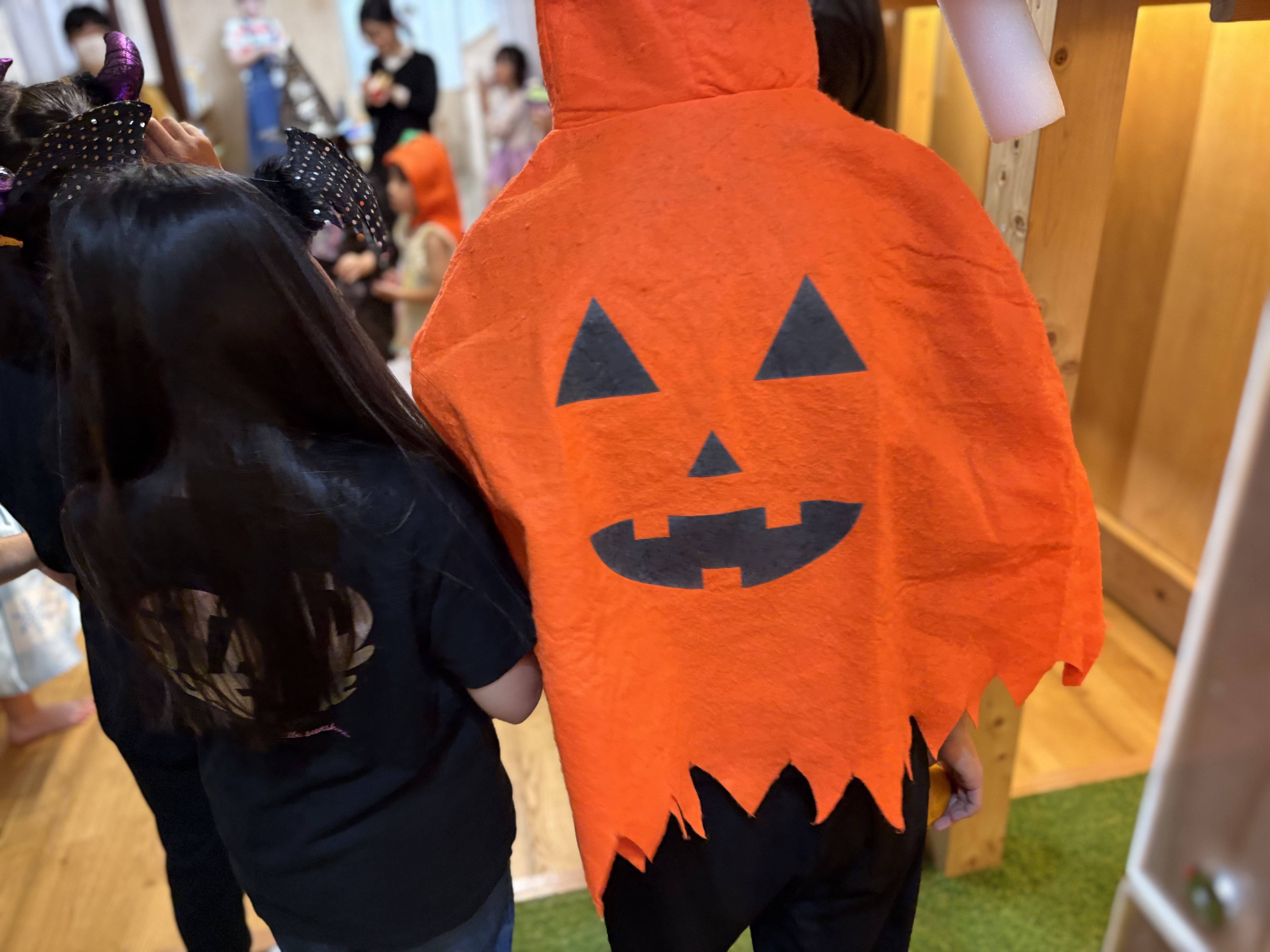 「『かぼちゃのポンチョでハイ、チーズ！』キュートな仮装お披露目」
お気に入りのかぼちゃポンチョや帽子を身につけ、ポーズを決めて照れくさそうに笑う可愛い一コマ。